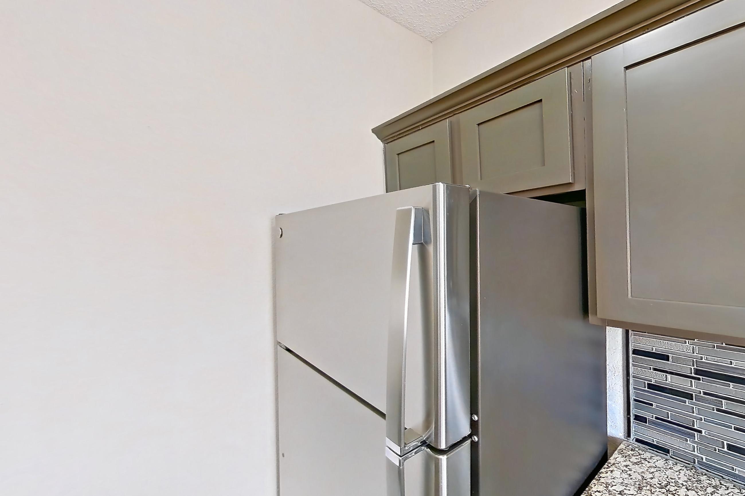 Kitchen with dishwasher, light countertops, light stone countertops, light wood-finish flooring, refrigerator, and stainless steel appliances, Apartment 1522 at Waterford on the Meadow