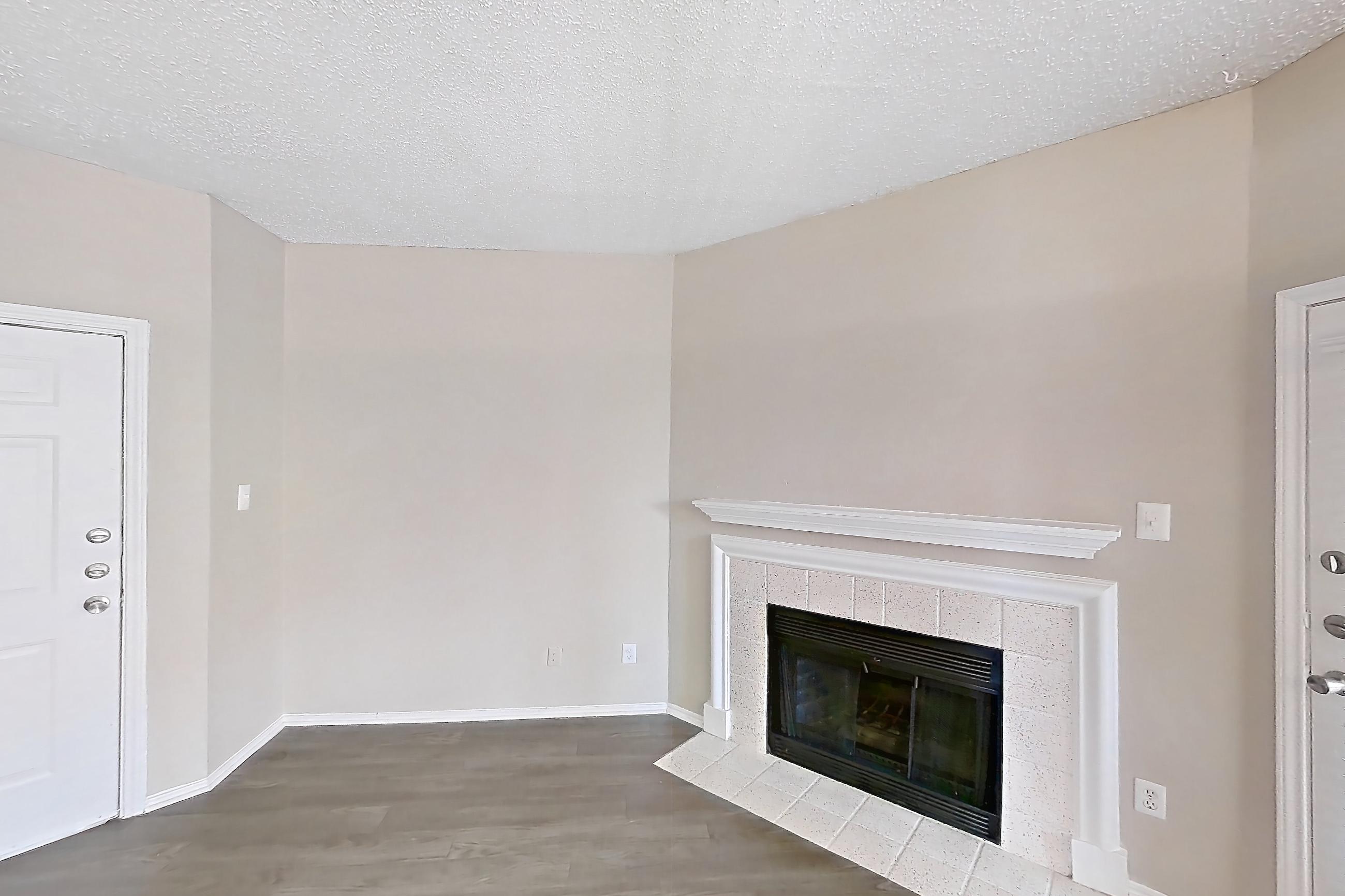 Living room with black appliances, dark wood-finish flooring, electric range, fireplace, light countertops, oven/range, refrigerator, stainless steel appliances, and tile fireplace, Apartment 3122 at Waterford on the Meadow