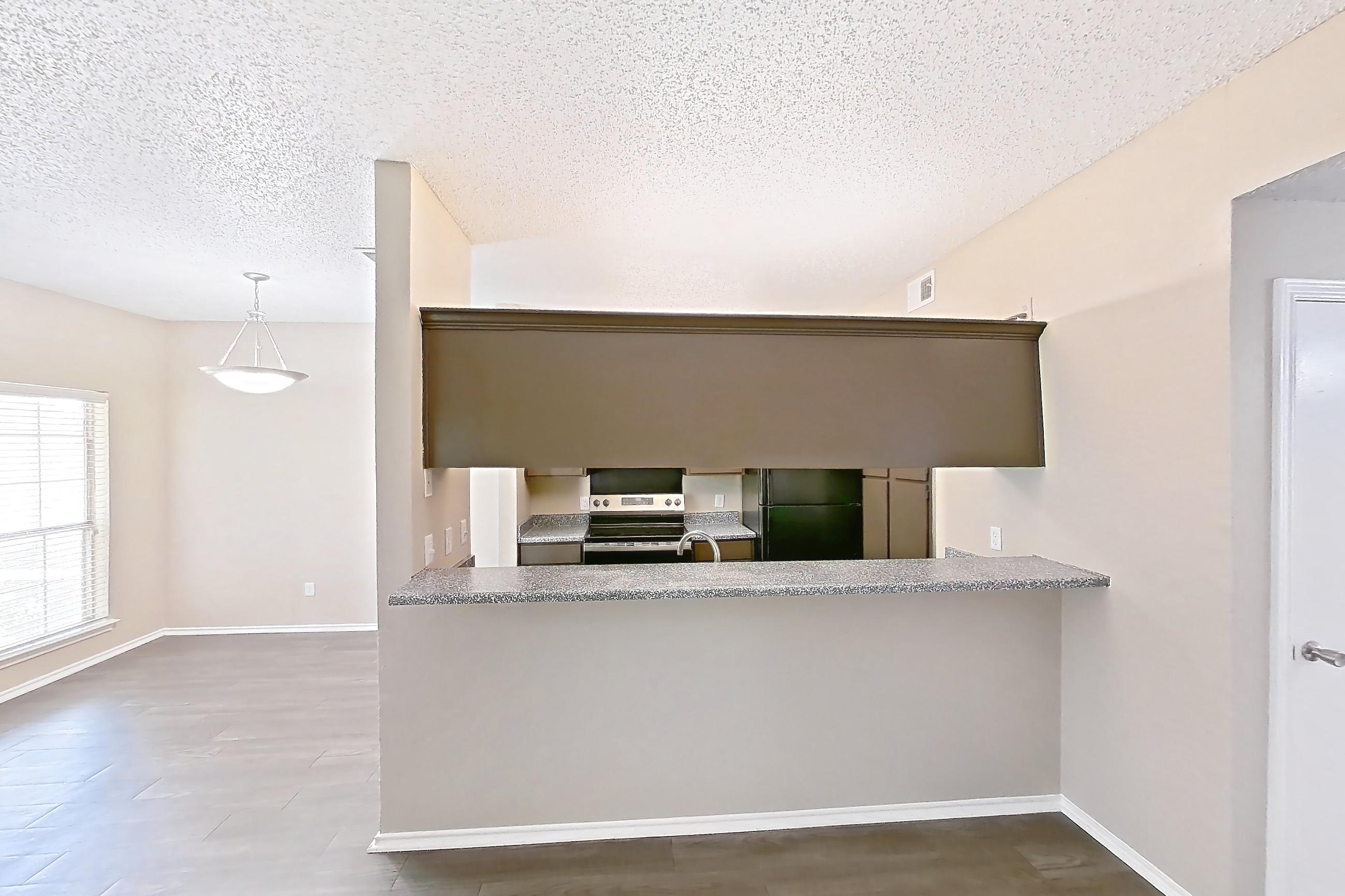 Living room with black appliances, dark wood-finish flooring, electric range, fireplace, light countertops, oven/range, refrigerator, stainless steel appliances, and tile fireplace, Apartment 3122 at Waterford on the Meadow