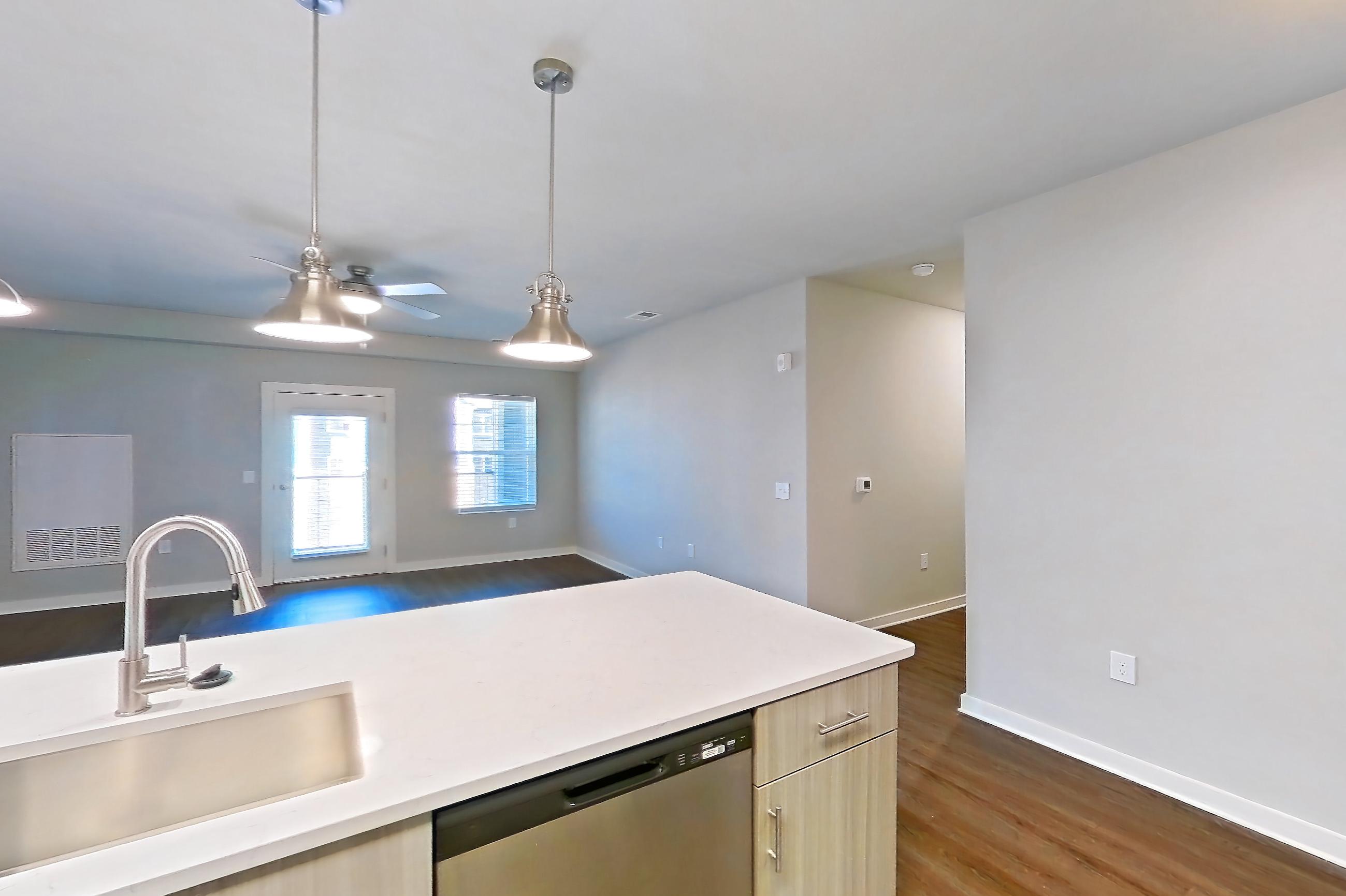 Kitchen with dark wood-finish flooring, dishwasher, electric range, light countertops, light stone countertops, light wood-finish flooring, microwave, oven/range, refrigerator, stainless steel appliances, and water & ice dispenser, Apartment 2-405 at The Soho