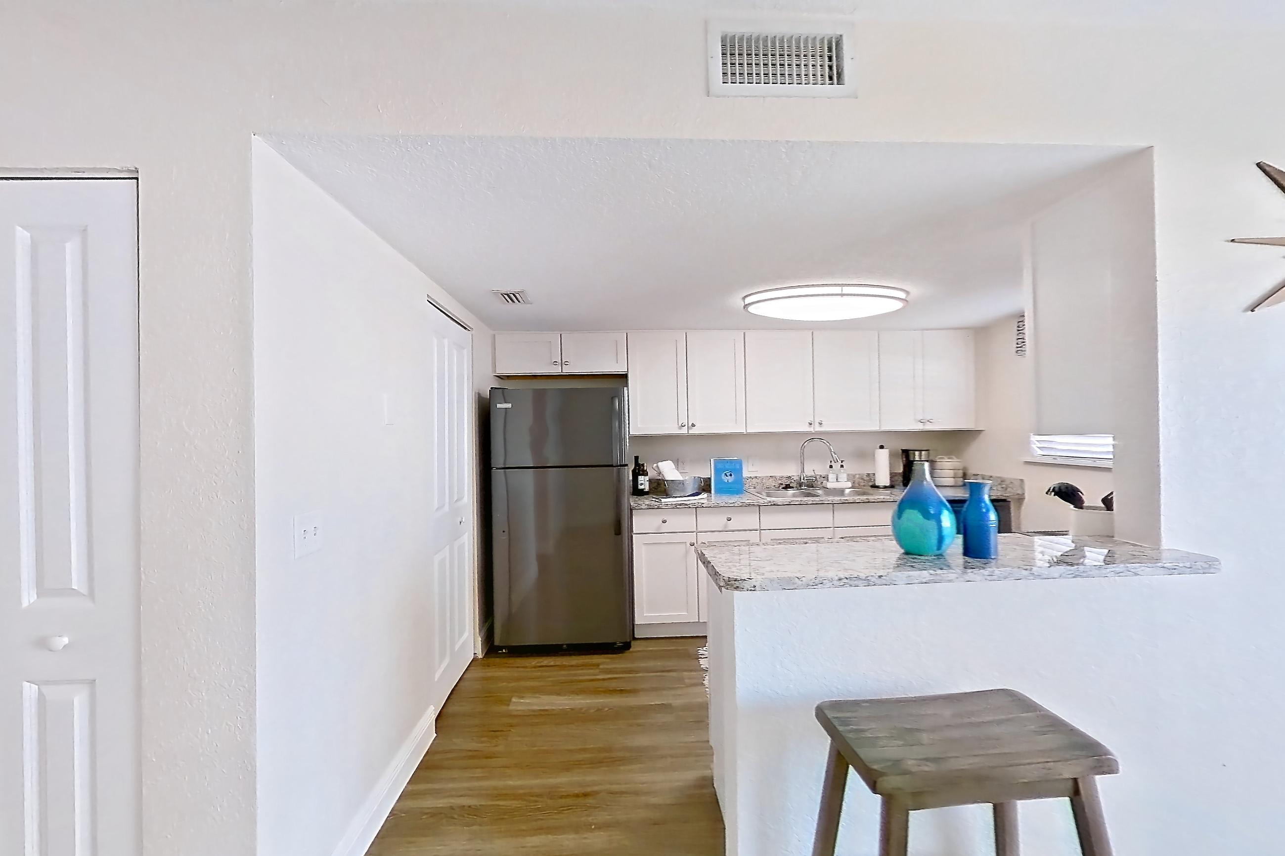 Dining room with dark wood-finish flooring, light stone countertops, refrigerator, and stainless steel appliances, Apartment A4 at Cypress West