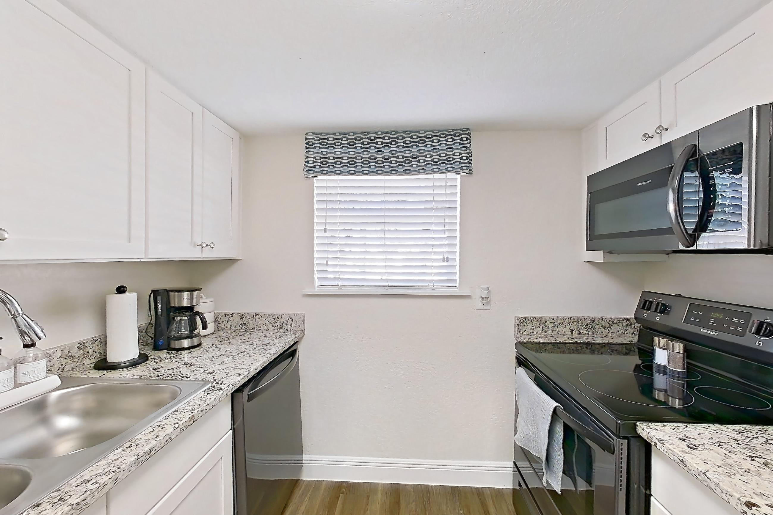 Kitchen with black appliances, dark wood-finish flooring, dishwasher, electric range, light countertops, light stone countertops, light wood-finish flooring, oven/range, and stainless steel appliances, Apartment A4 at Cypress West