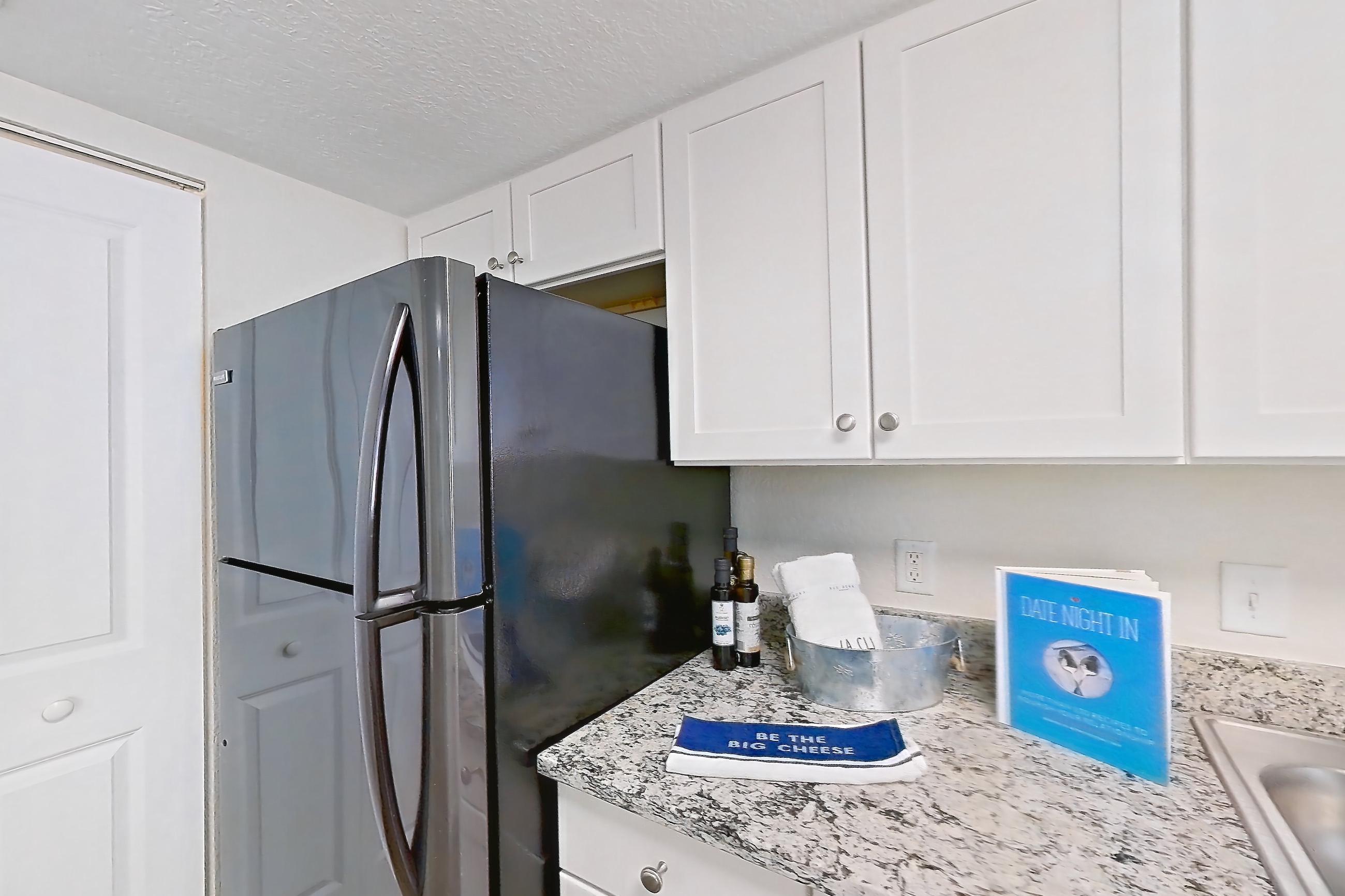 Kitchen with black appliances, dark wood-finish flooring, dishwasher, electric range, light countertops, light stone countertops, light wood-finish flooring, oven/range, and stainless steel appliances, Apartment A4 at Cypress West