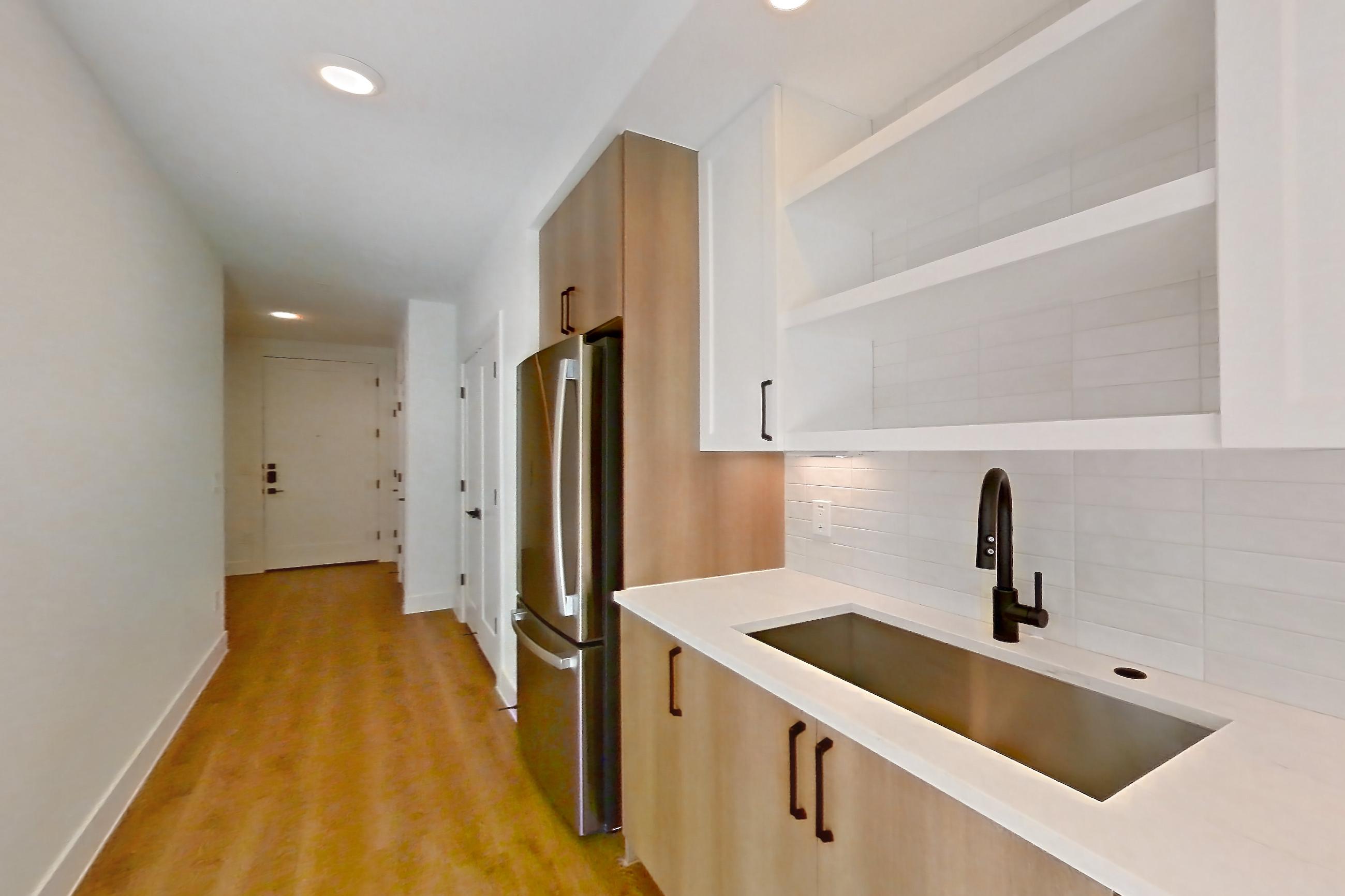 Kitchen with dishwasher, electric range, light countertops, light stone countertops, light wood-finish flooring, microwave, oven/range, refrigerator, and stainless steel appliances, Apartment 505 at The Watson