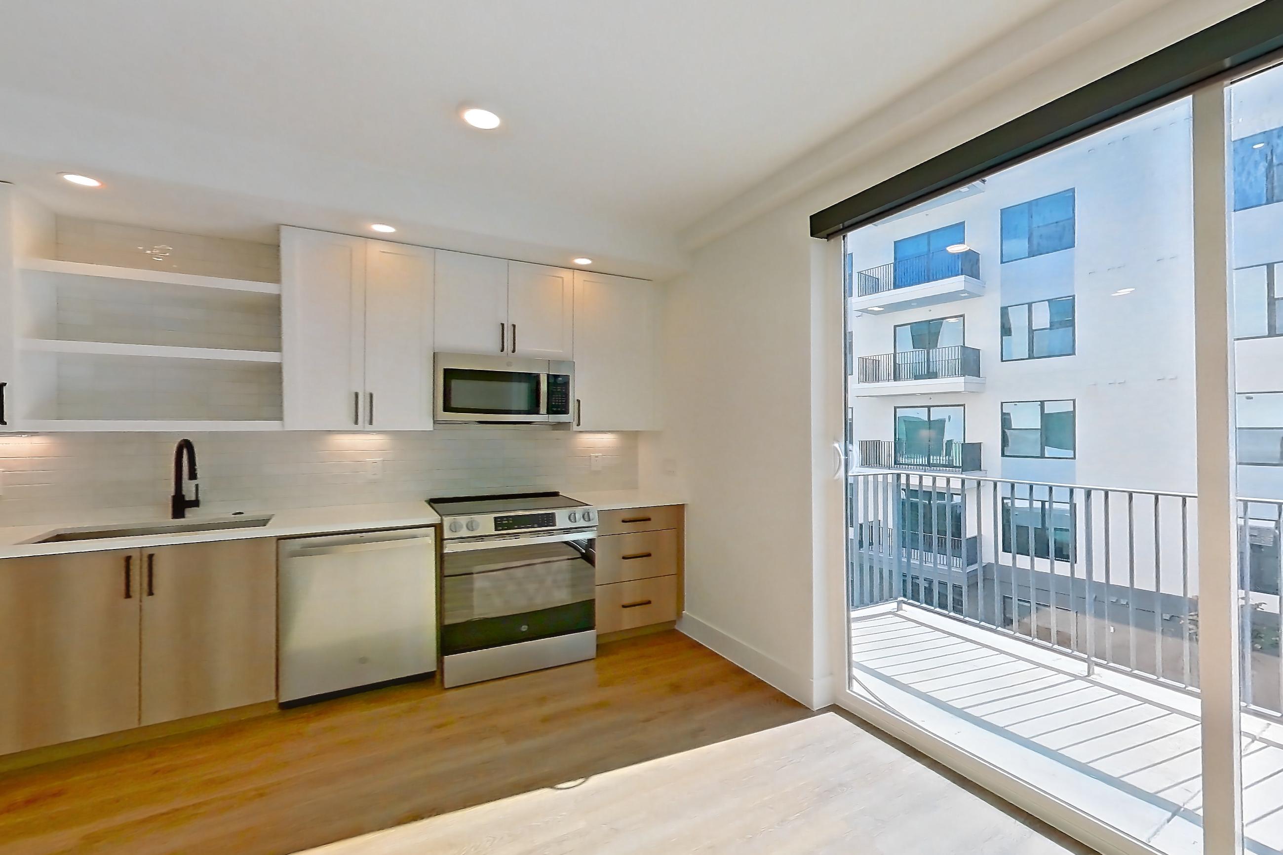 Living space with dishwasher, electric range, light countertops, light wood-finish flooring, microwave, oven/range, refrigerator, and stainless steel appliances, Apartment 505 at The Watson