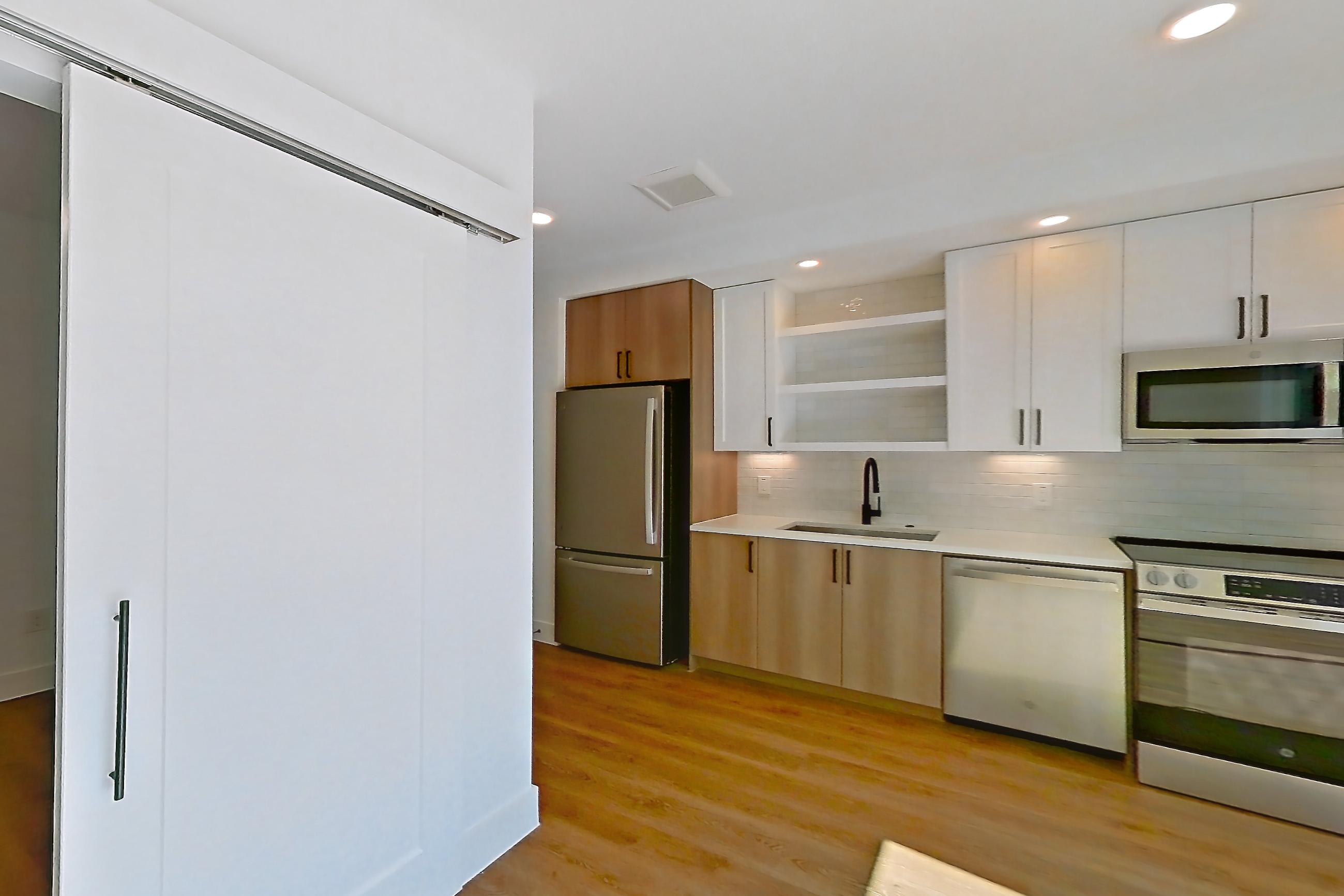 Living space with dishwasher, electric range, light countertops, light wood-finish flooring, microwave, oven/range, refrigerator, and stainless steel appliances, Apartment 505 at The Watson