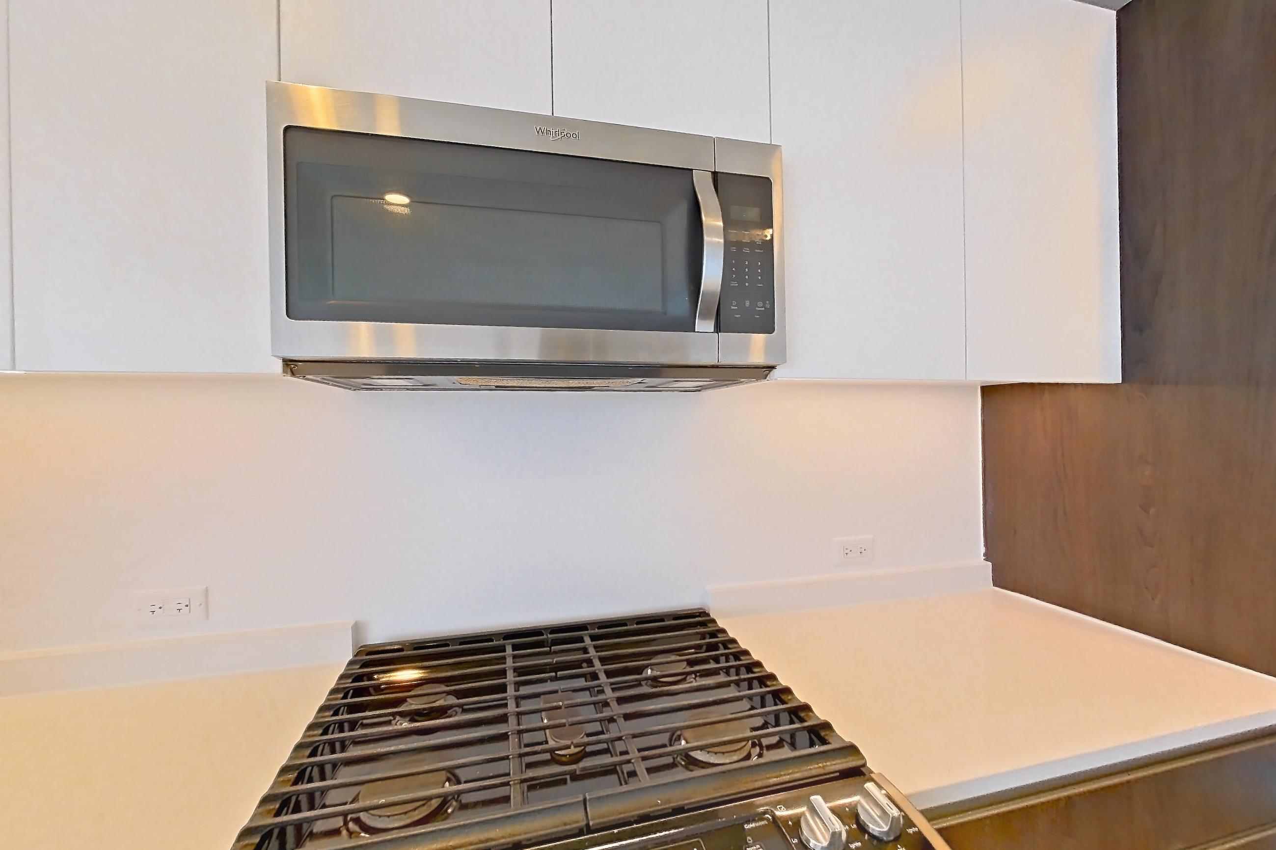 Kitchen with gas range, light countertops, light wood-finish flooring, microwave, oven/range, and stainless steel appliances, Apartment 3JP PH1-G at Jackson Park