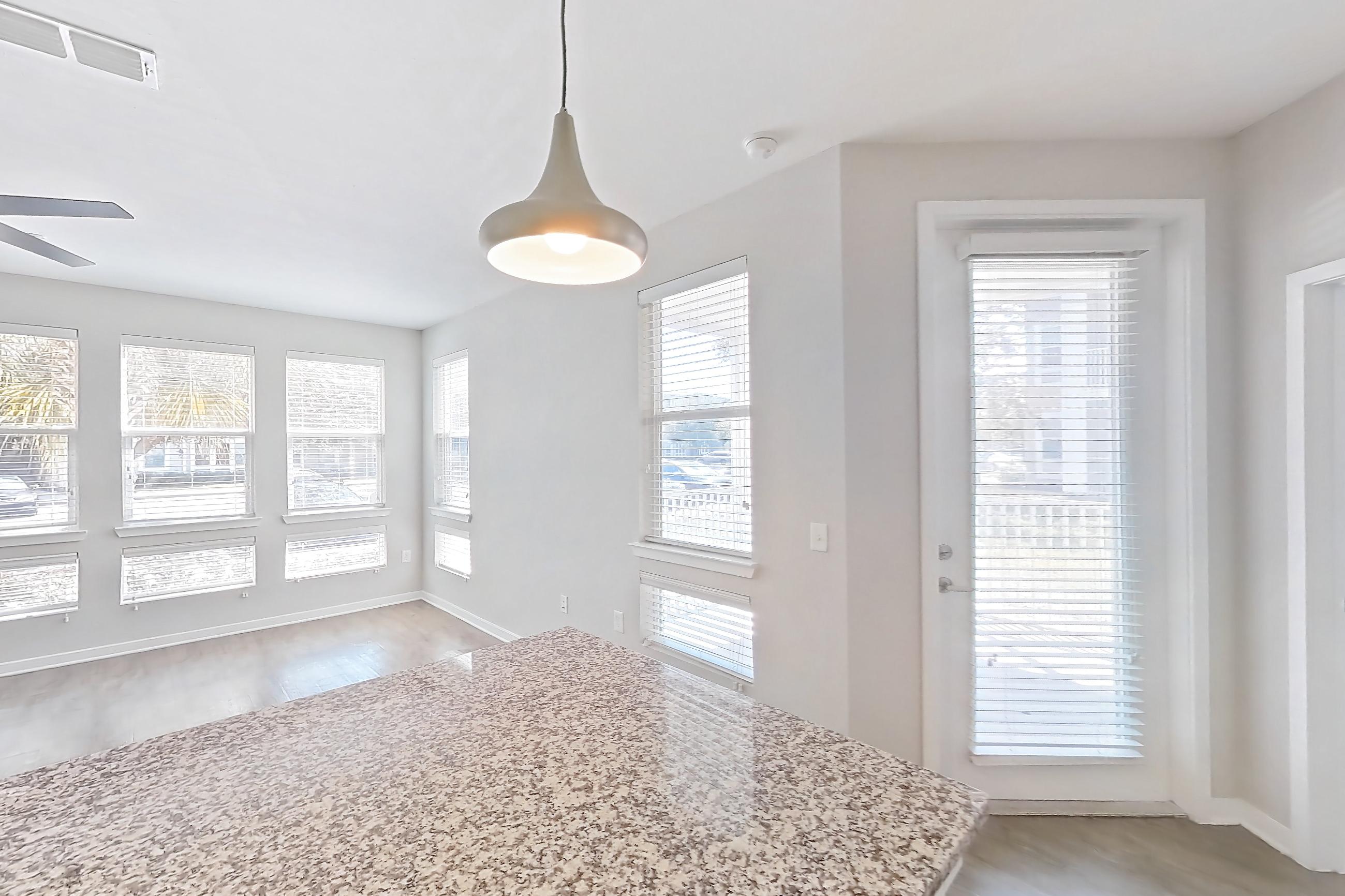 Kitchen with dishwasher, electric range, kitchen island, light countertops, light stone countertops, light wood-finish flooring, oven/range, and stainless steel appliances, Apartment 101 at Lake Nona Ariel Apartments
