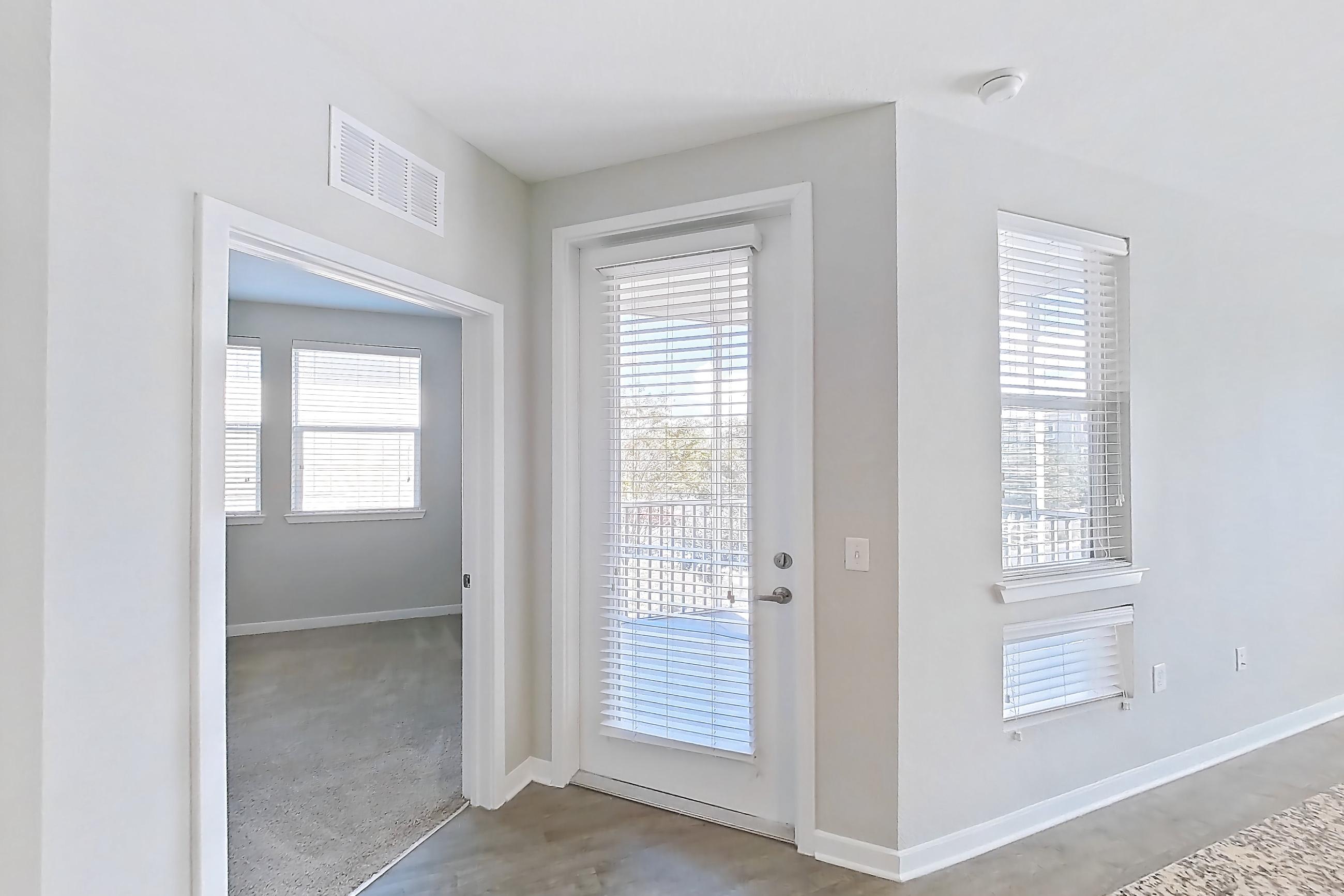 Kitchen with dishwasher, kitchen island, light stone countertops, light wood-finish flooring, refrigerator, and stainless steel appliances, Apartment 208 at Lake Nona Ariel Apartments