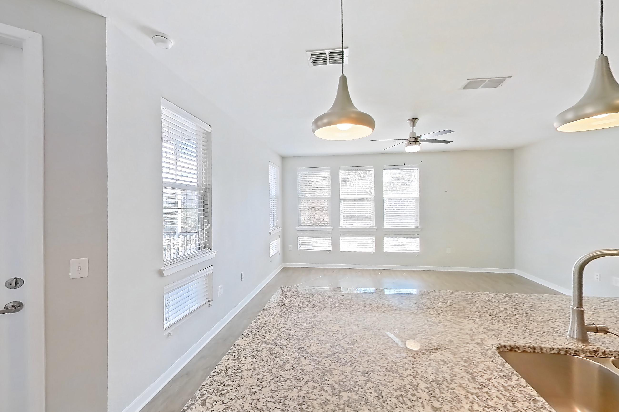 Kitchen with dishwasher, kitchen island, light stone countertops, light wood-finish flooring, refrigerator, and stainless steel appliances, Apartment 208 at Lake Nona Ariel Apartments