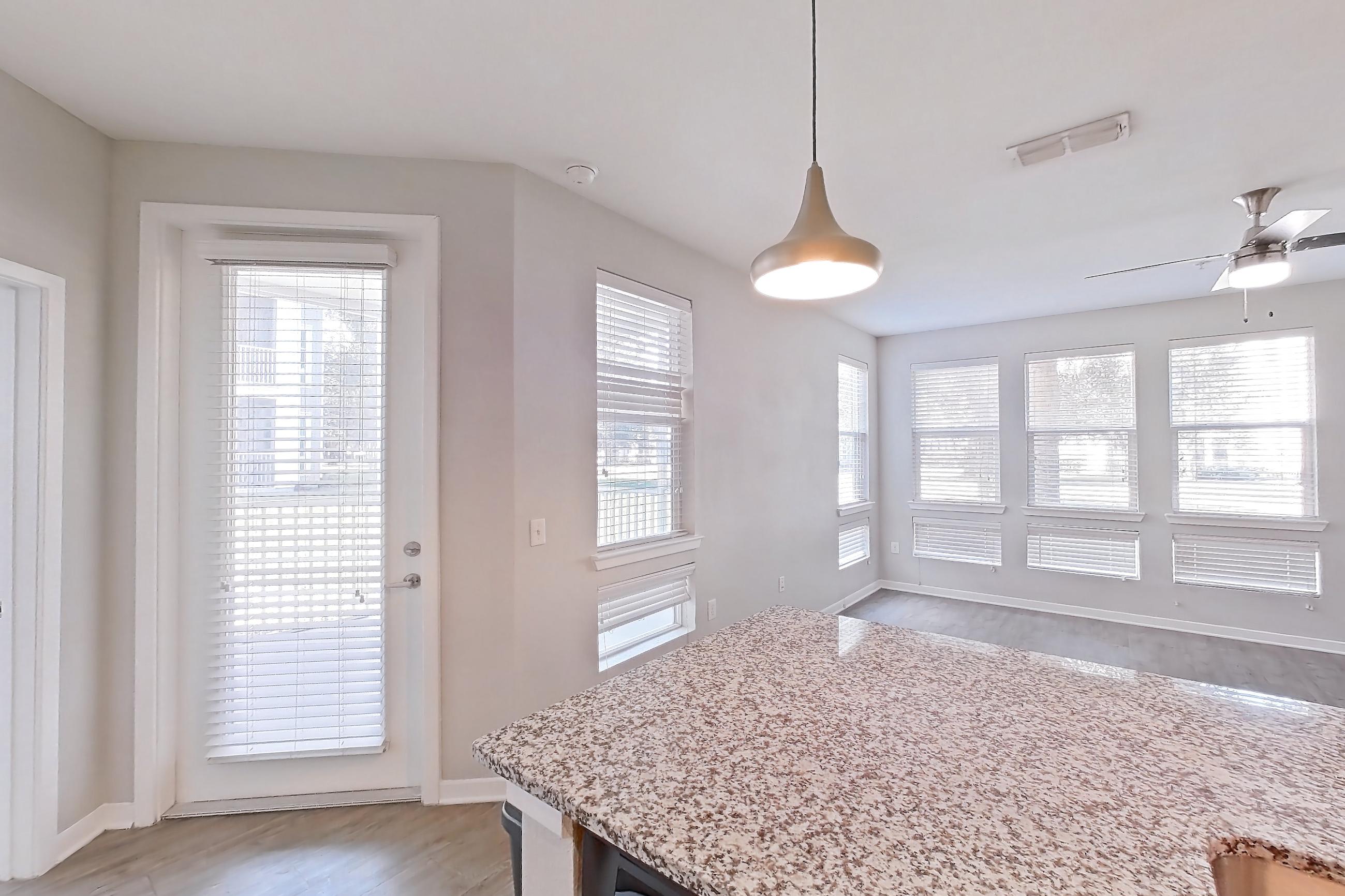 Kitchen with dishwasher, light countertops, light stone countertops, light wood-finish flooring, refrigerator, and stainless steel appliances, Apartment 103 at Lake Nona Ariel Apartments
