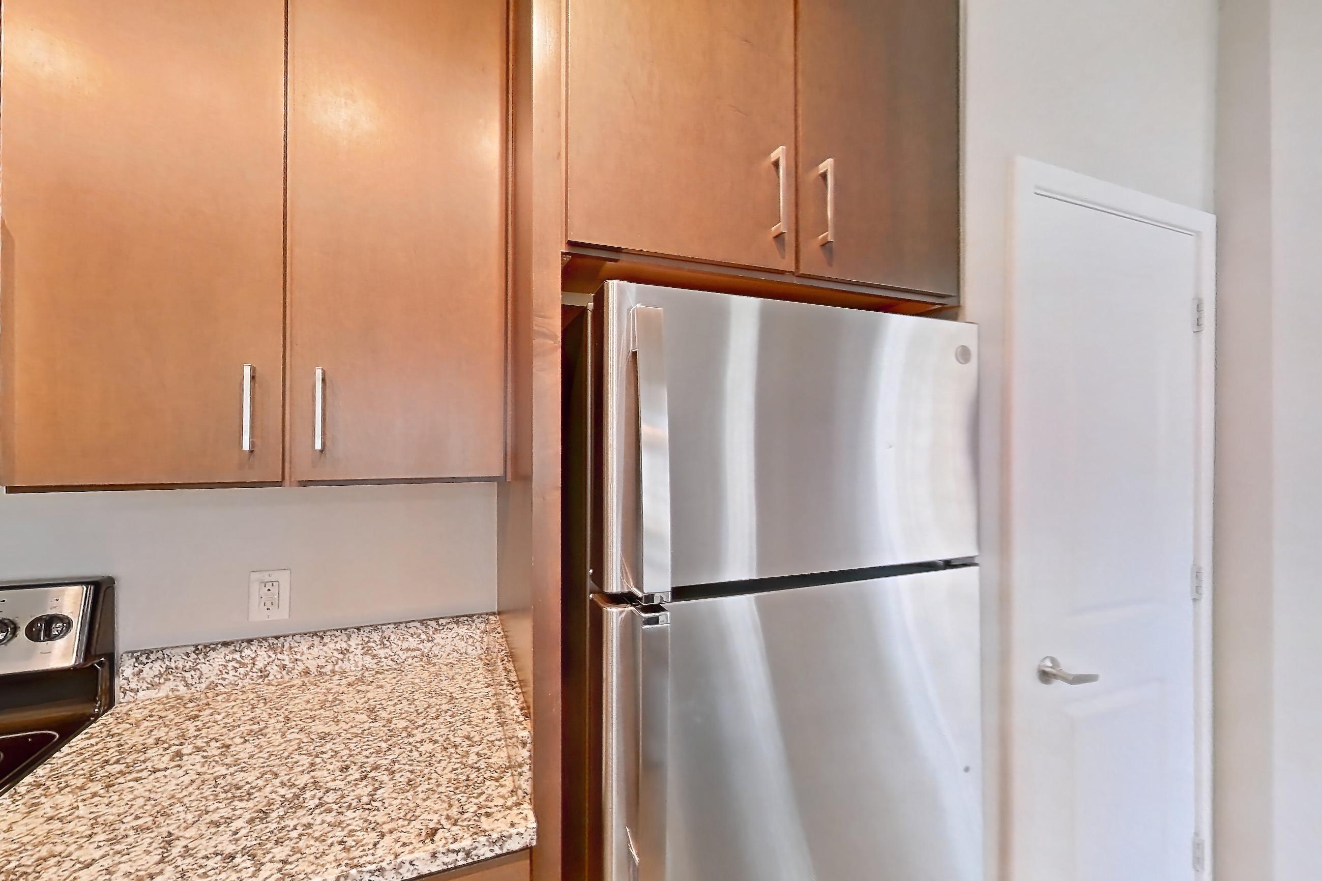 Kitchen with dishwasher, light countertops, light stone countertops, light wood-finish flooring, refrigerator, and stainless steel appliances, Apartment 103 at Lake Nona Ariel Apartments