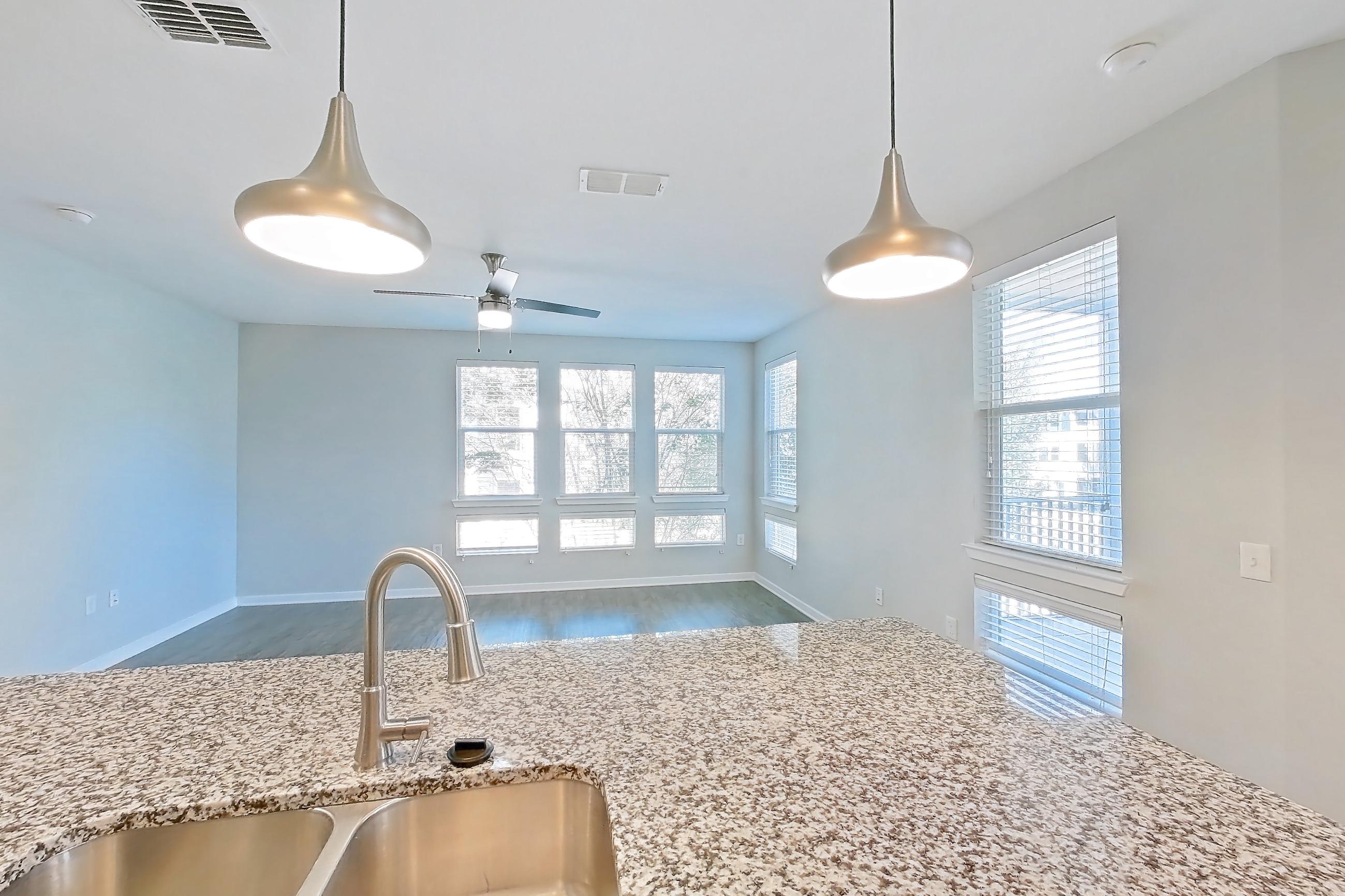 Kitchen with dishwasher, electric range, light stone countertops, light wood-finish flooring, oven/range, refrigerator, and stainless steel appliances, Apartment 208 at Lake Nona Ariel Apartments