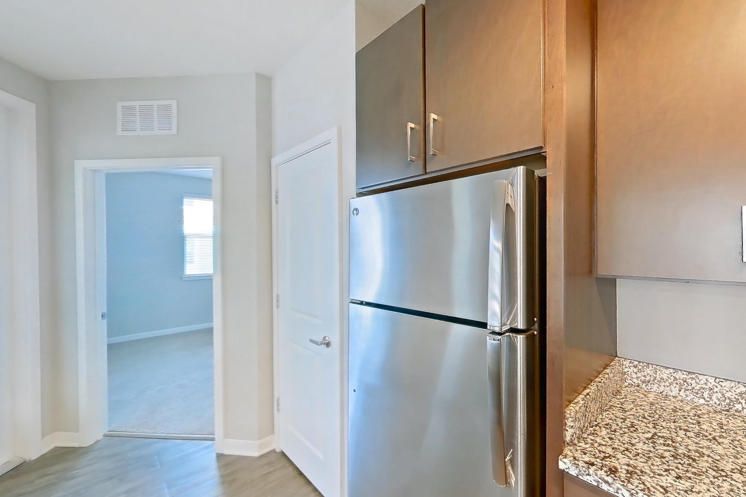 Kitchen with dishwasher, electric range, light stone countertops, light wood-finish flooring, oven/range, refrigerator, and stainless steel appliances, Apartment 208 at Lake Nona Ariel Apartments