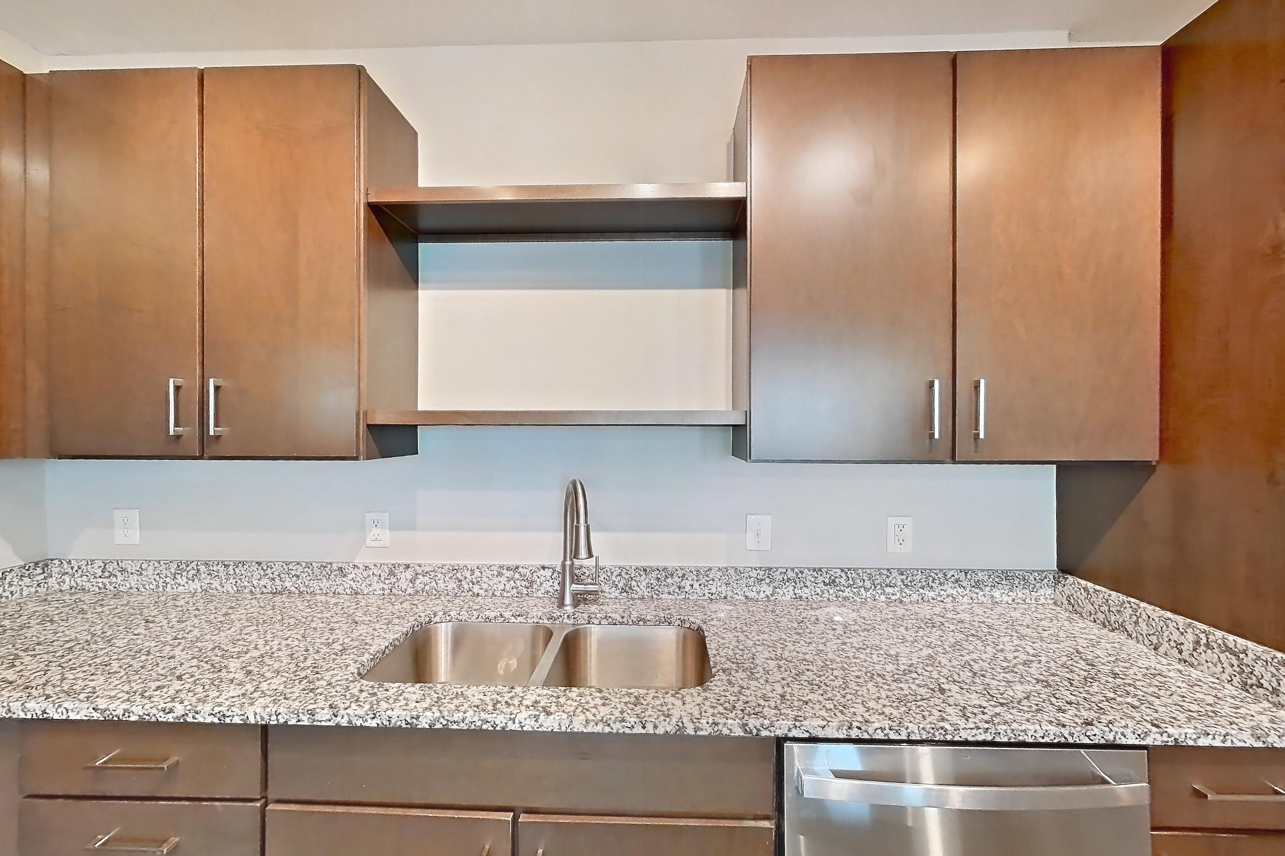 Kitchen with dishwasher, electric range, light countertops, light stone countertops, light wood-finish flooring, microwave, oven/range, refrigerator, and stainless steel appliances, Apartment 208 at Lake Nona Ariel Apartments