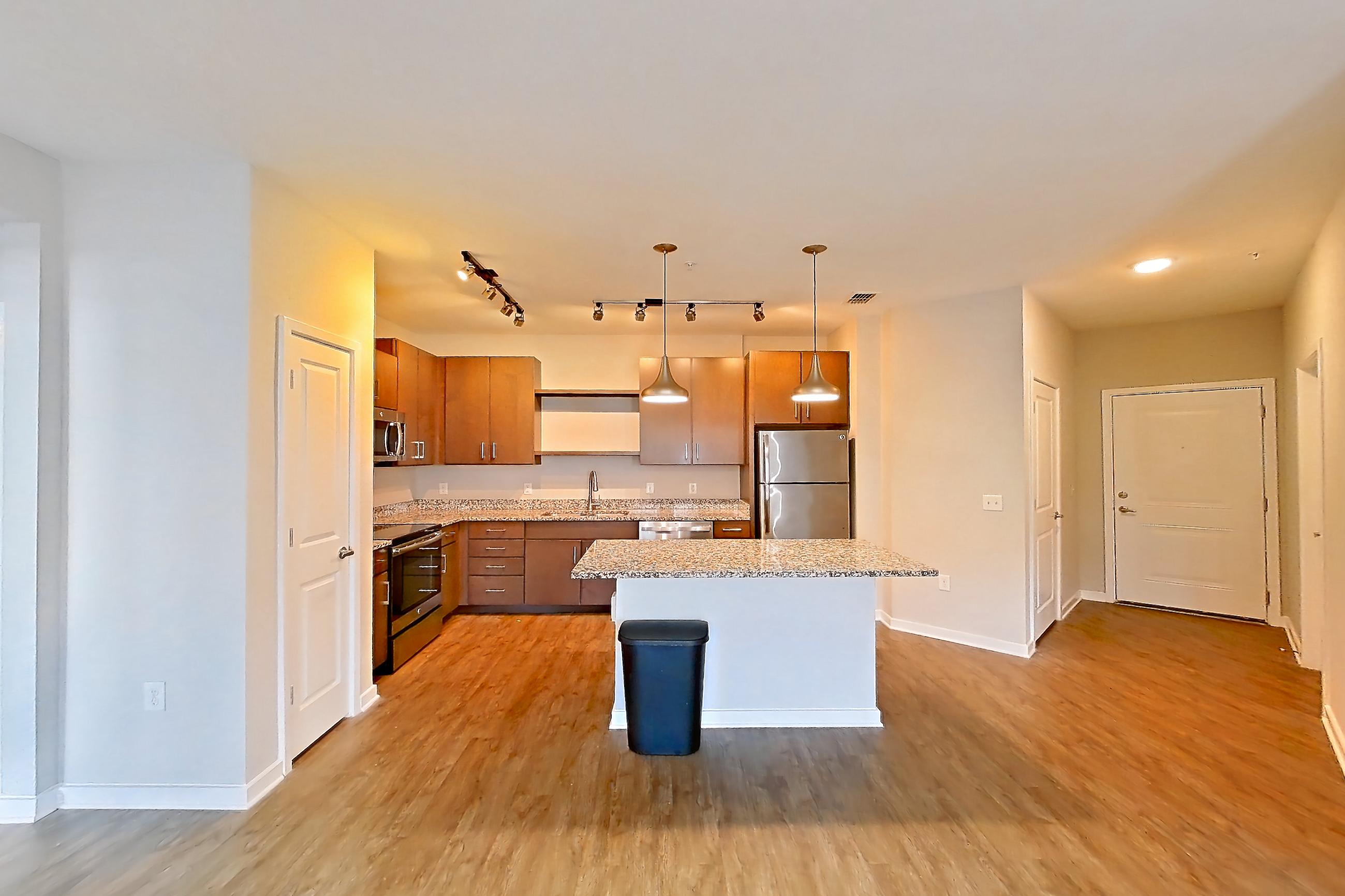 Living room with dishwasher, electric range, light stone countertops, light wood-finish flooring, oven/range, refrigerator, and stainless steel appliances, Apartment 208 at Lake Nona Ariel Apartments