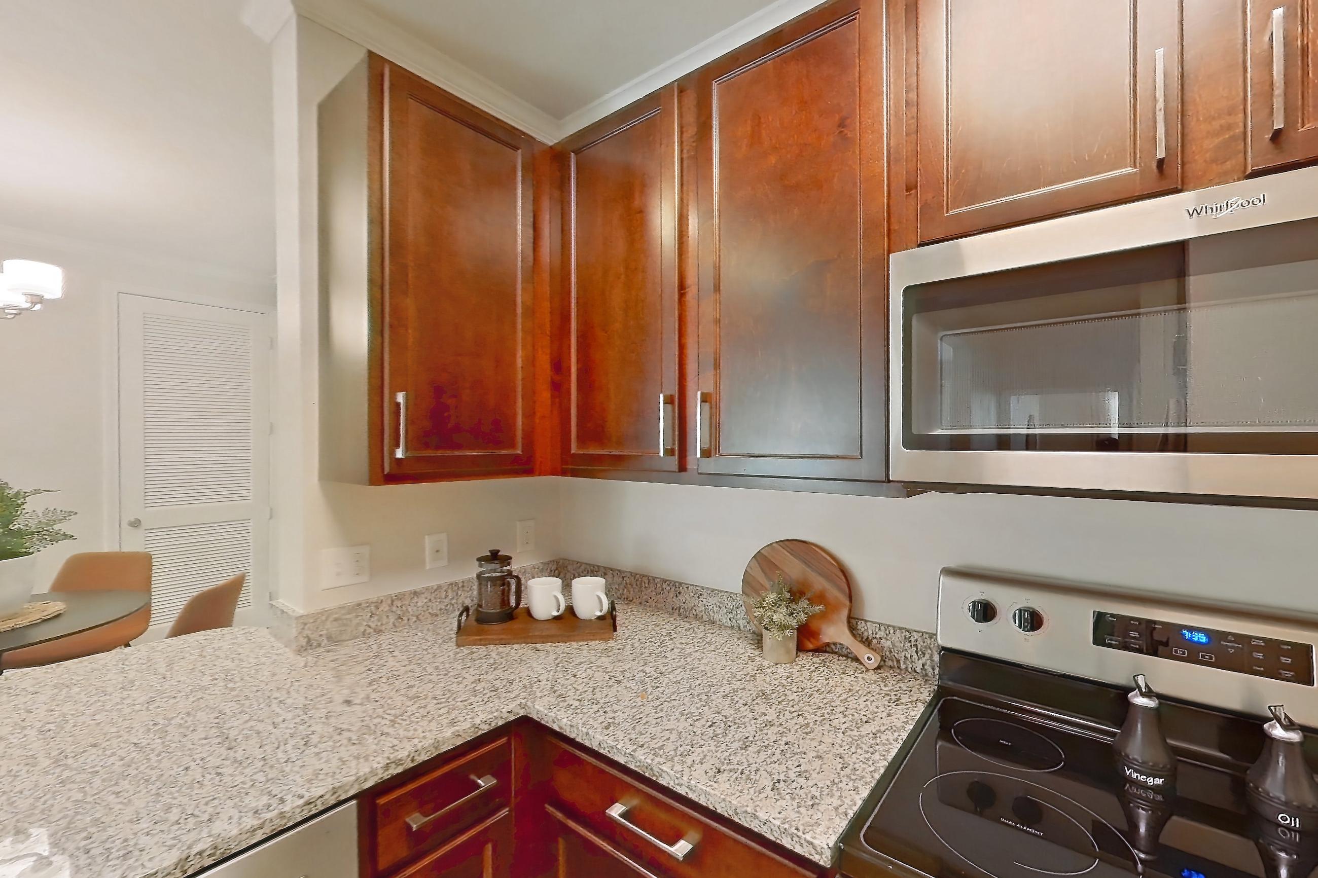 Kitchen with dishwasher, electric range, in-unit laundry, light stone countertops, light wood-finish flooring, oven/range, and stainless steel appliances, Apartment 0112 at Lake Nona Water Mark