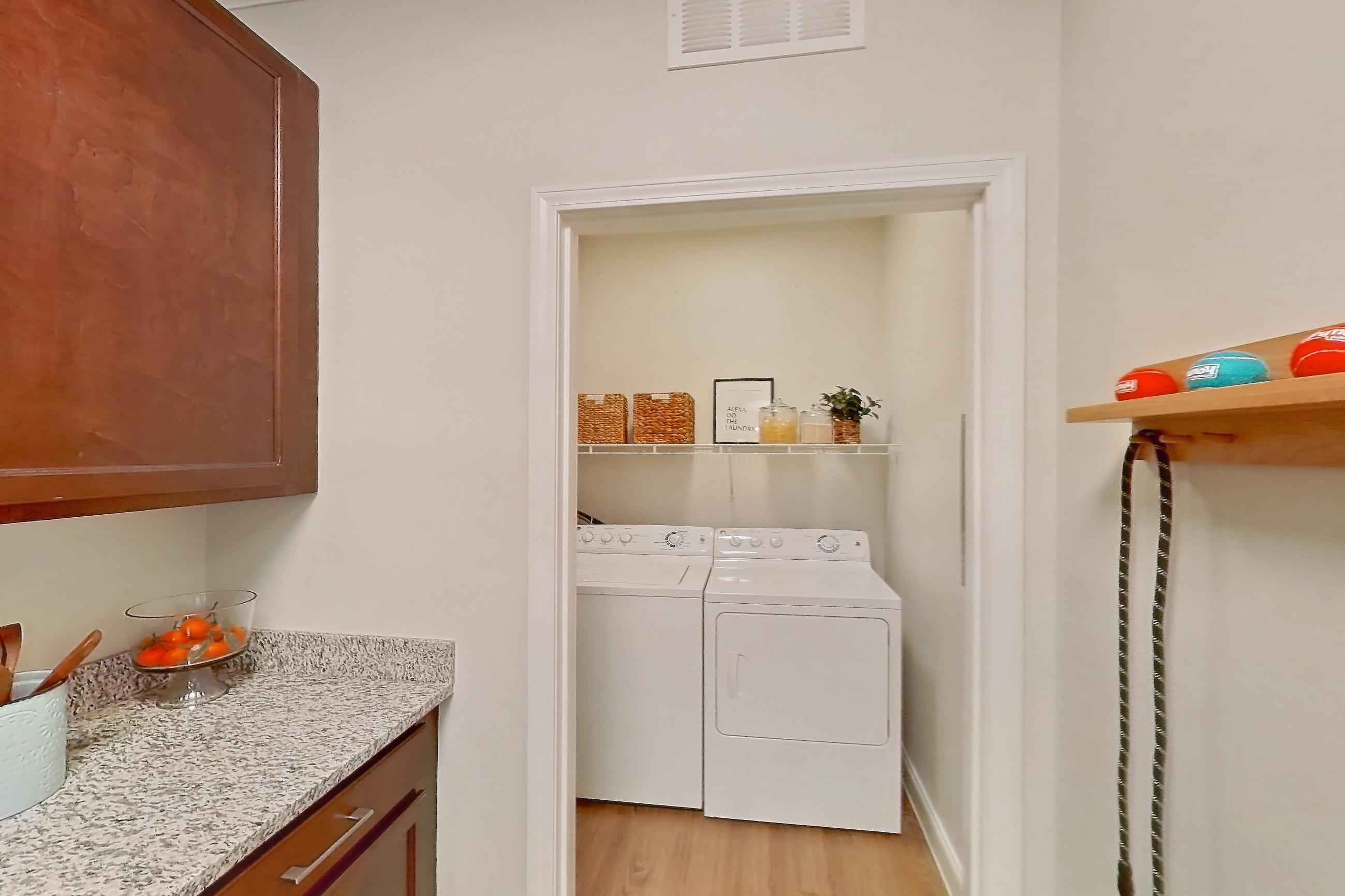 Kitchen with dishwasher, electric range, in-unit laundry, light stone countertops, light wood-finish flooring, oven/range, and stainless steel appliances, Apartment 0112 at Lake Nona Water Mark