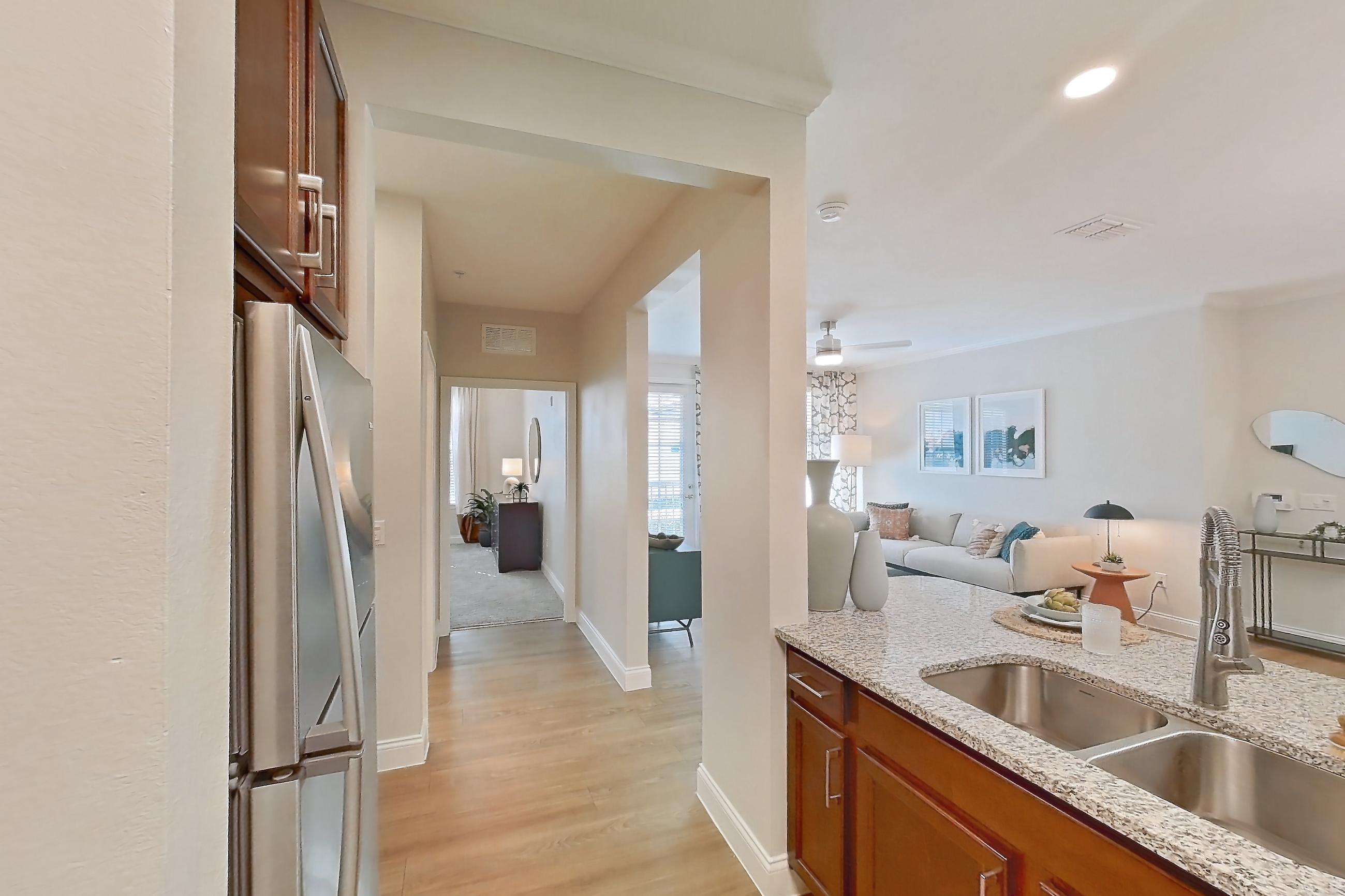 Kitchen with dishwasher, electric range, in-unit laundry, light stone countertops, light wood-finish flooring, oven/range, and stainless steel appliances, Apartment 0112 at Lake Nona Water Mark