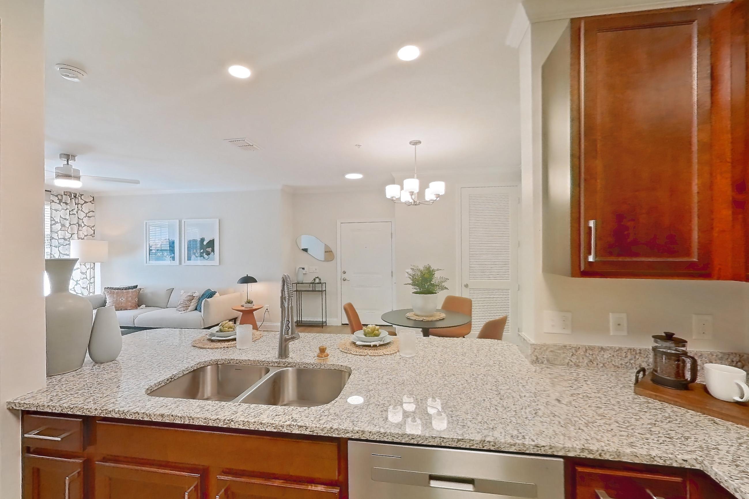 Kitchen with dishwasher, electric range, in-unit laundry, light stone countertops, light wood-finish flooring, oven/range, and stainless steel appliances, Apartment 0112 at Lake Nona Water Mark