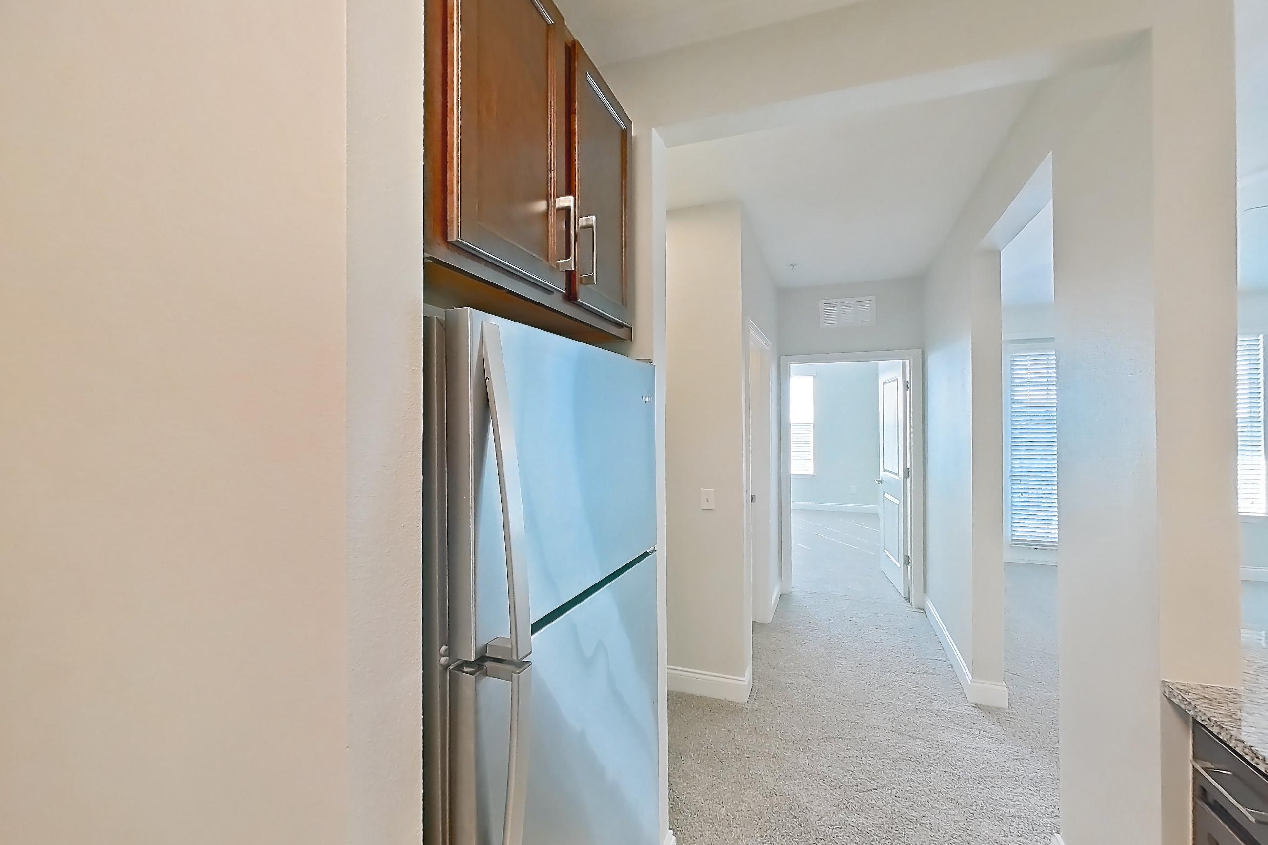 Kitchen with dishwasher, electric range, light carpet, light countertops, light stone countertops, light tile flooring, microwave, oven/range, refrigerator, and stainless steel appliances, Apartment 0132 at Lake Nona Water Mark