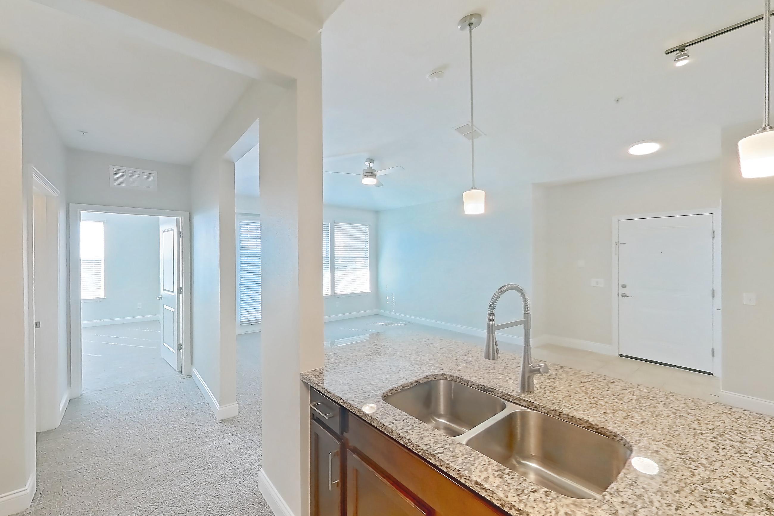 Kitchen with dishwasher, electric range, light carpet, light countertops, light stone countertops, light tile flooring, microwave, oven/range, refrigerator, and stainless steel appliances, Apartment 0132 at Lake Nona Water Mark
