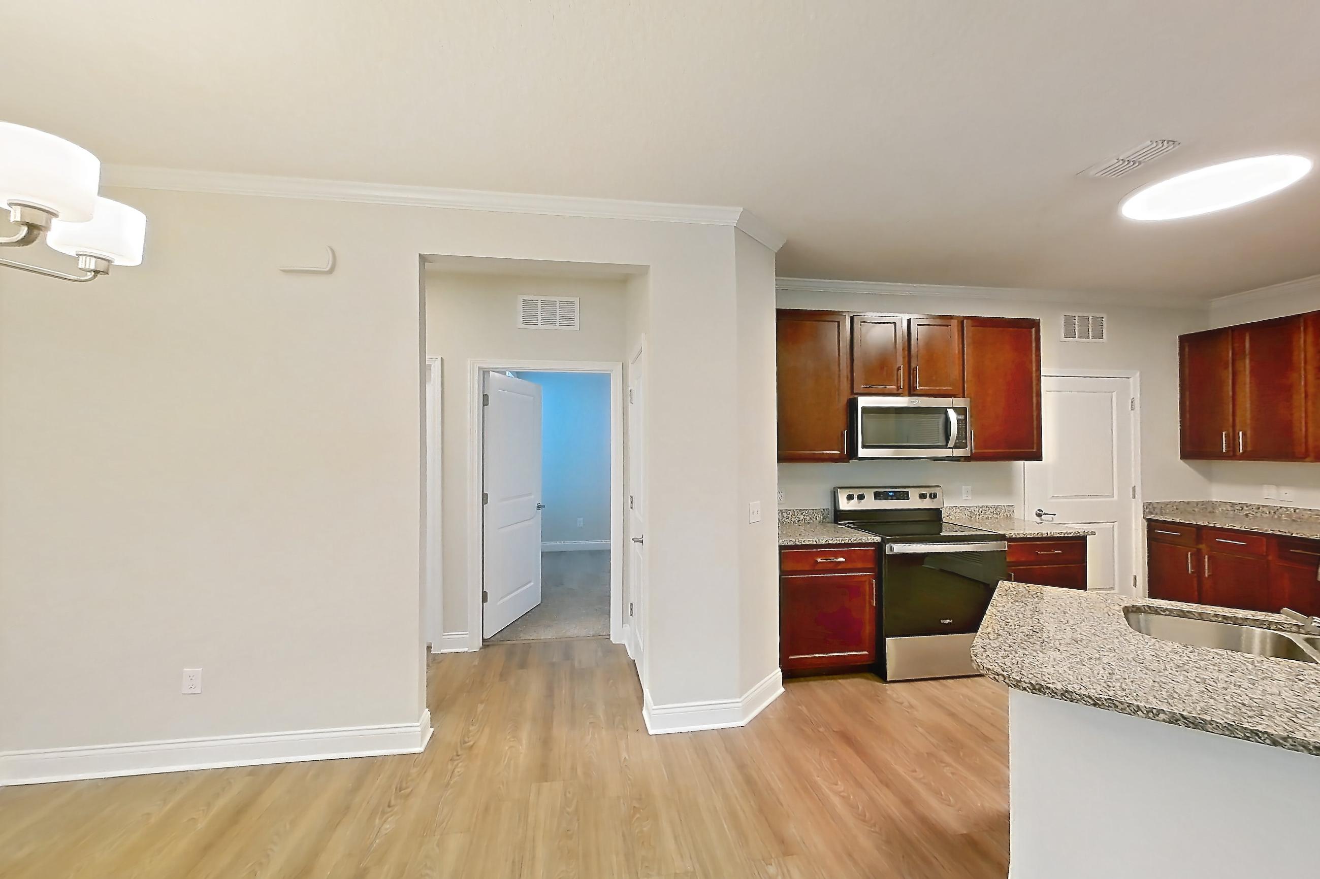 Living room with electric range, light stone countertops, light wood-finish flooring, oven/range, refrigerator, and stainless steel appliances, Apartment 0316 at Lake Nona Water Mark