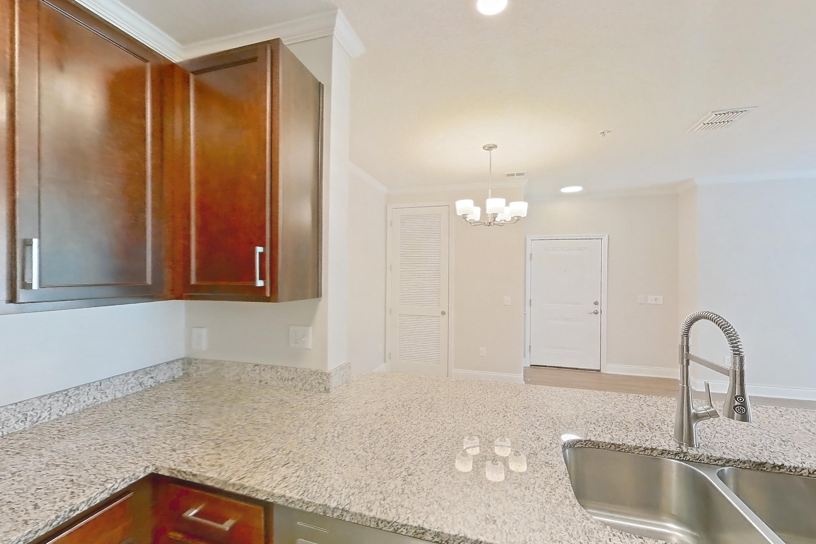Kitchen with dishwasher, electric range, light countertops, light stone countertops, light wood-finish flooring, oven/range, refrigerator, and stainless steel appliances, Apartment 1111 at Lake Nona Water Mark
