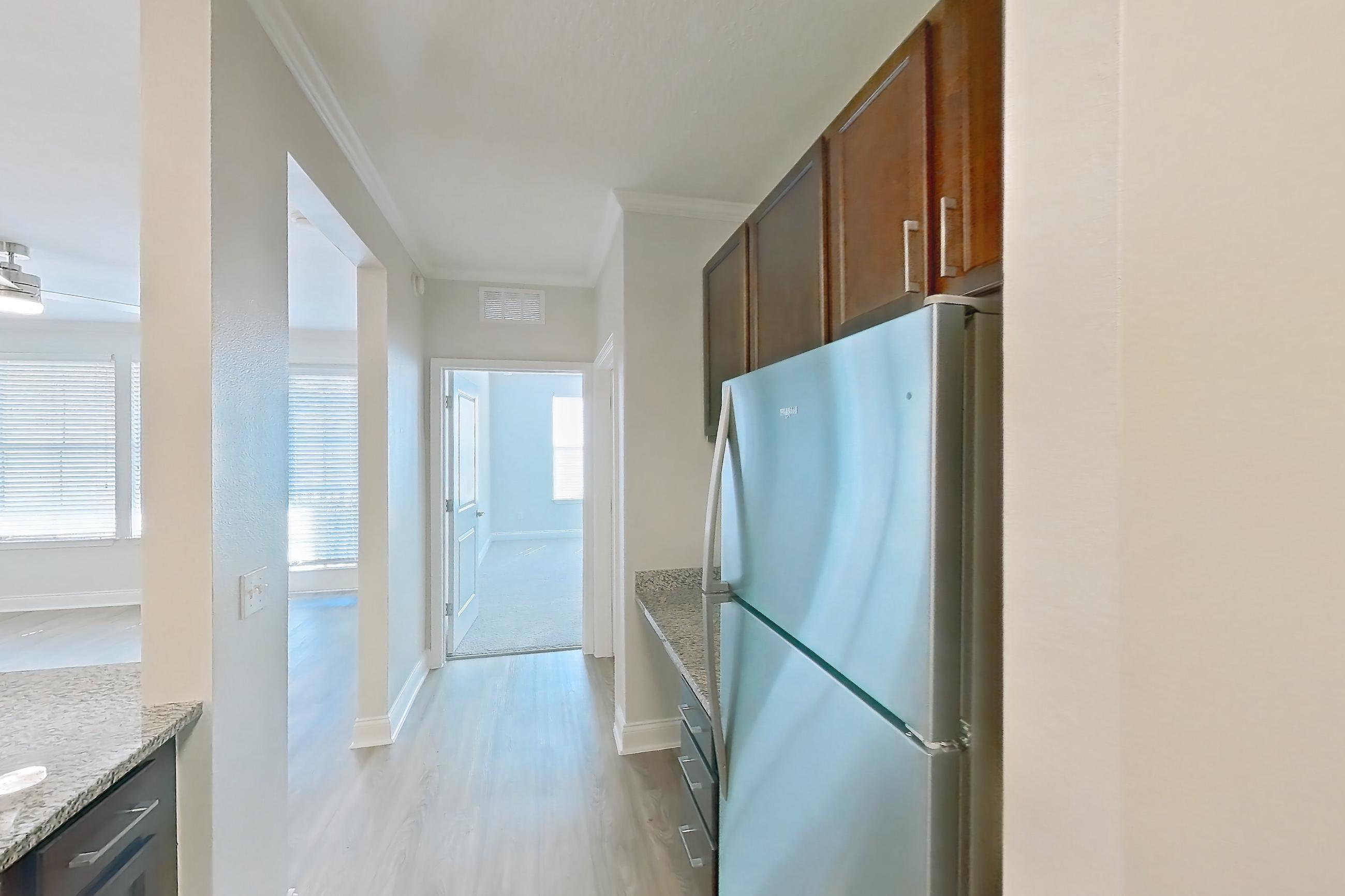 Kitchen with dishwasher, electric range, light countertops, light stone countertops, light wood-finish flooring, oven/range, refrigerator, and stainless steel appliances, Apartment 1111 at Lake Nona Water Mark