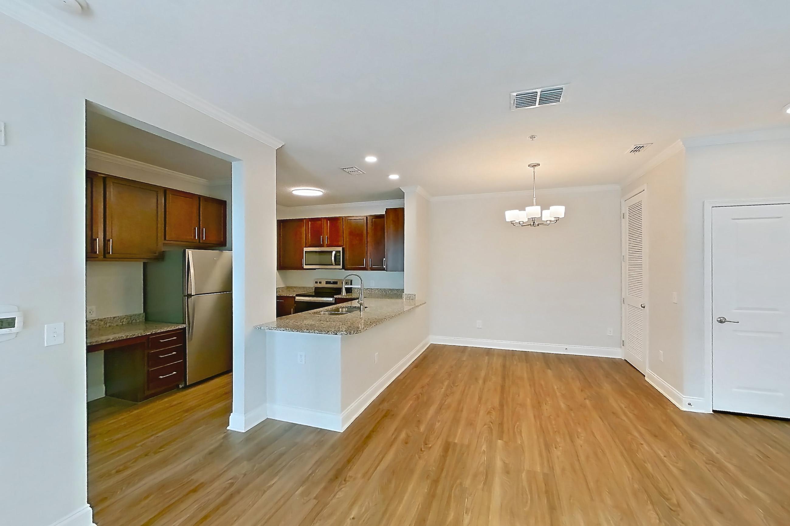 Living room with dark wood-finish flooring, electric range, light stone countertops, light wood-finish flooring, oven/range, refrigerator, and stainless steel appliances, Apartment 1111 at Lake Nona Water Mark