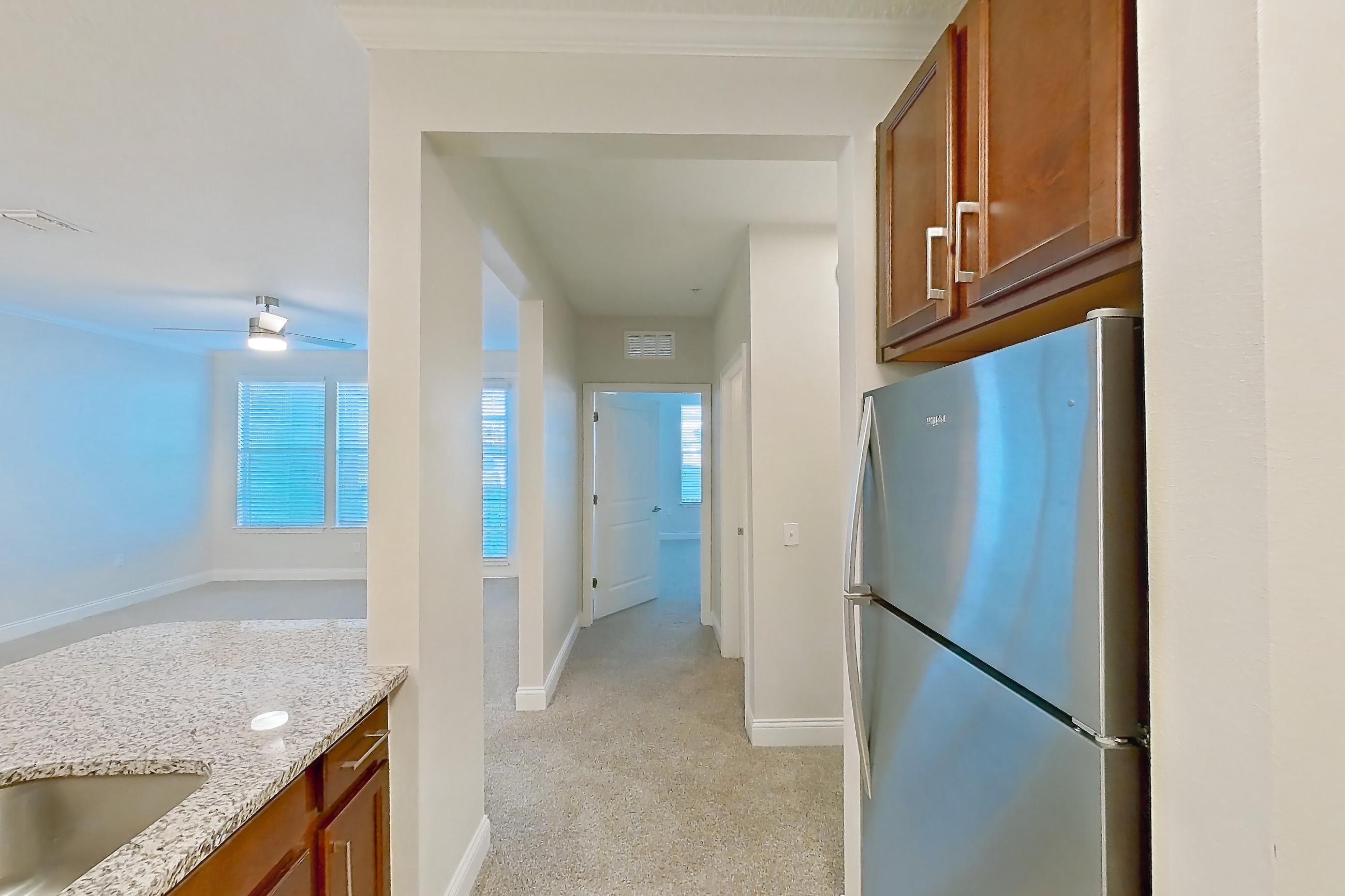Kitchen with dishwasher, light carpet, light stone countertops, light tile flooring, refrigerator, and stainless steel appliances, Apartment 1521 at Lake Nona Water Mark