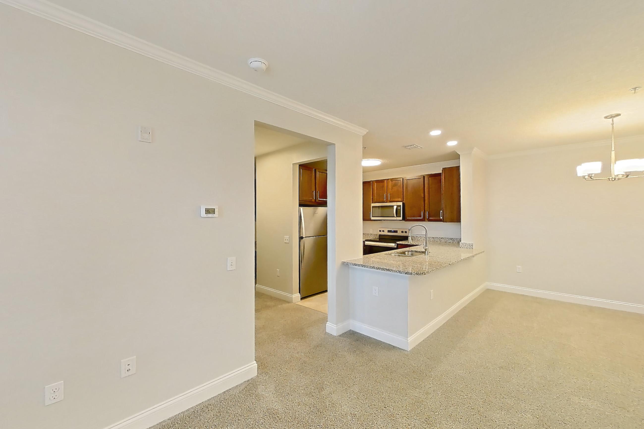 Living room with electric range, light carpet, light stone countertops, oven/range, refrigerator, and stainless steel appliances, Apartment 1521 at Lake Nona Water Mark