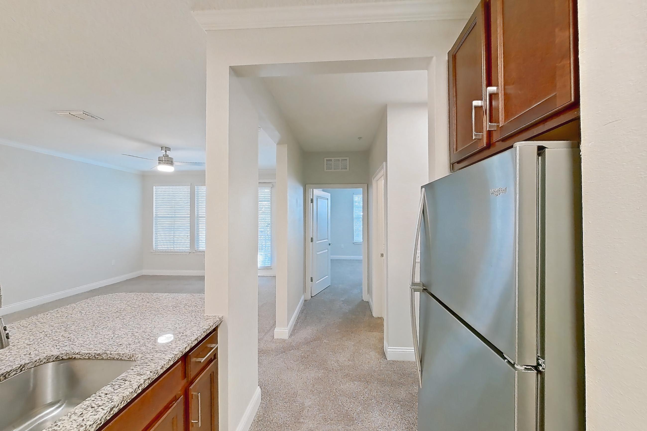 Kitchen with dishwasher, light carpet, light stone countertops, light tile flooring, refrigerator, and stainless steel appliances, Apartment 1524 at Lake Nona Water Mark