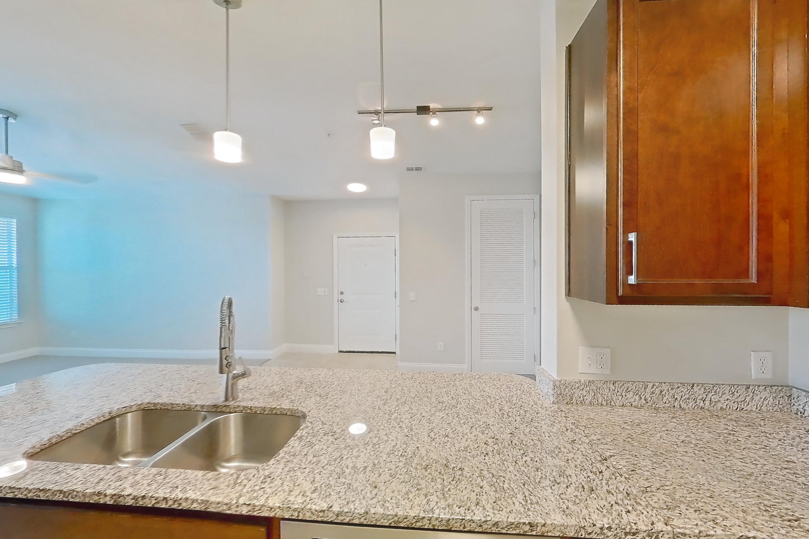 Kitchen with dishwasher, electric range, light countertops, light stone countertops, light tile flooring, microwave, oven/range, refrigerator, and stainless steel appliances, Apartment 1632 at Lake Nona Water Mark