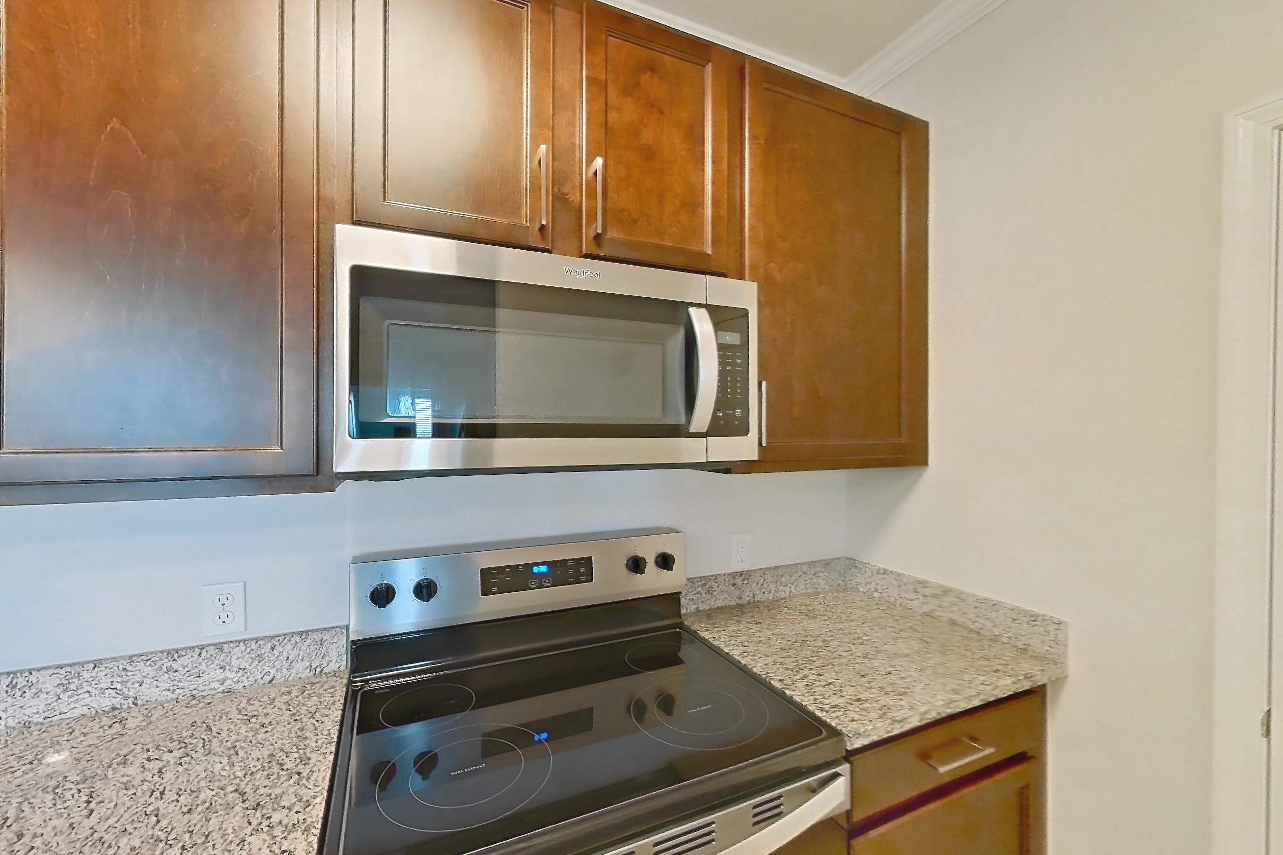 Kitchen with dishwasher, electric range, light countertops, light stone countertops, light tile flooring, microwave, oven/range, refrigerator, and stainless steel appliances, Apartment 1632 at Lake Nona Water Mark