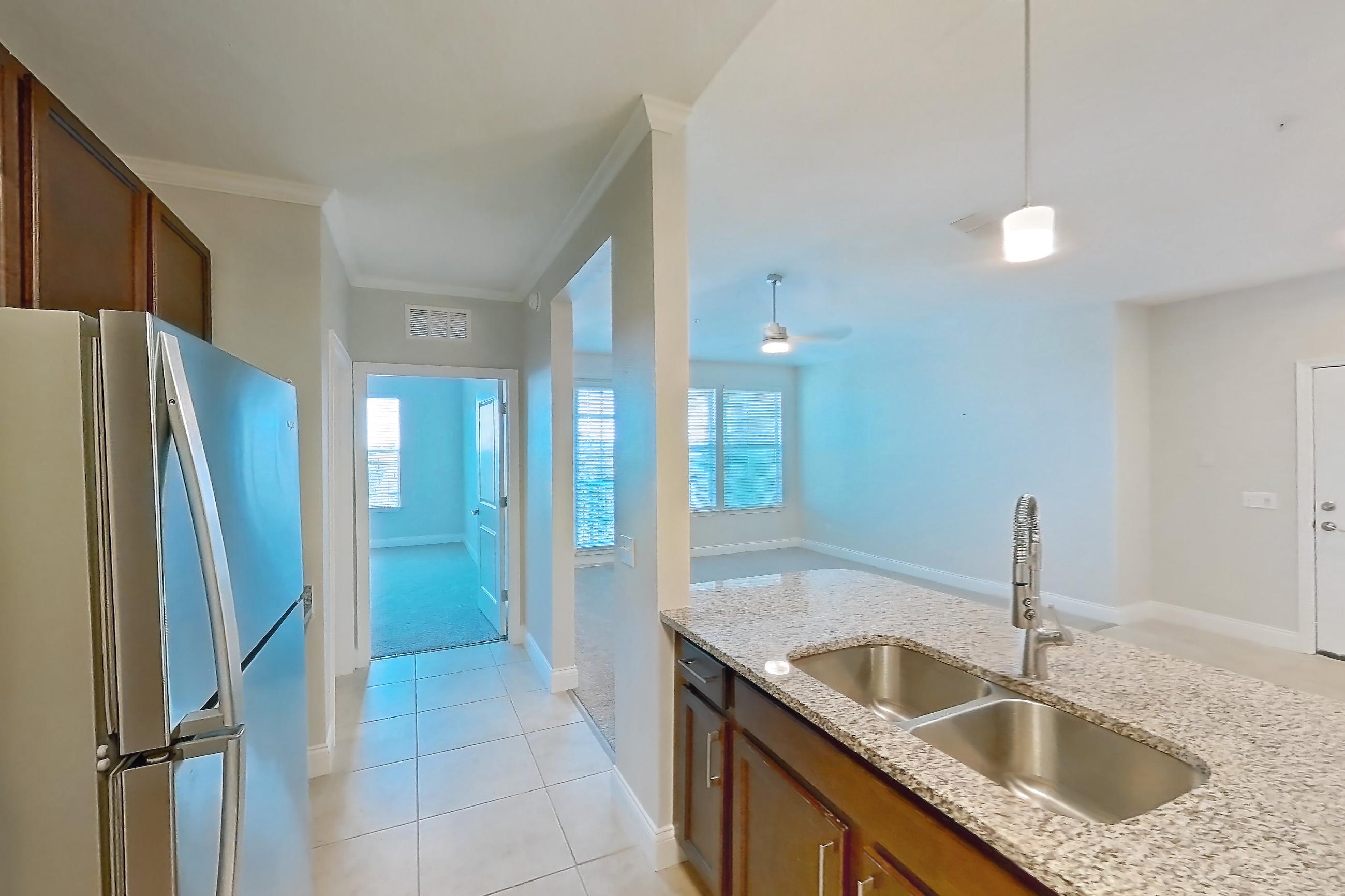 Kitchen with dishwasher, electric range, light countertops, light stone countertops, light tile flooring, microwave, oven/range, refrigerator, and stainless steel appliances, Apartment 1632 at Lake Nona Water Mark