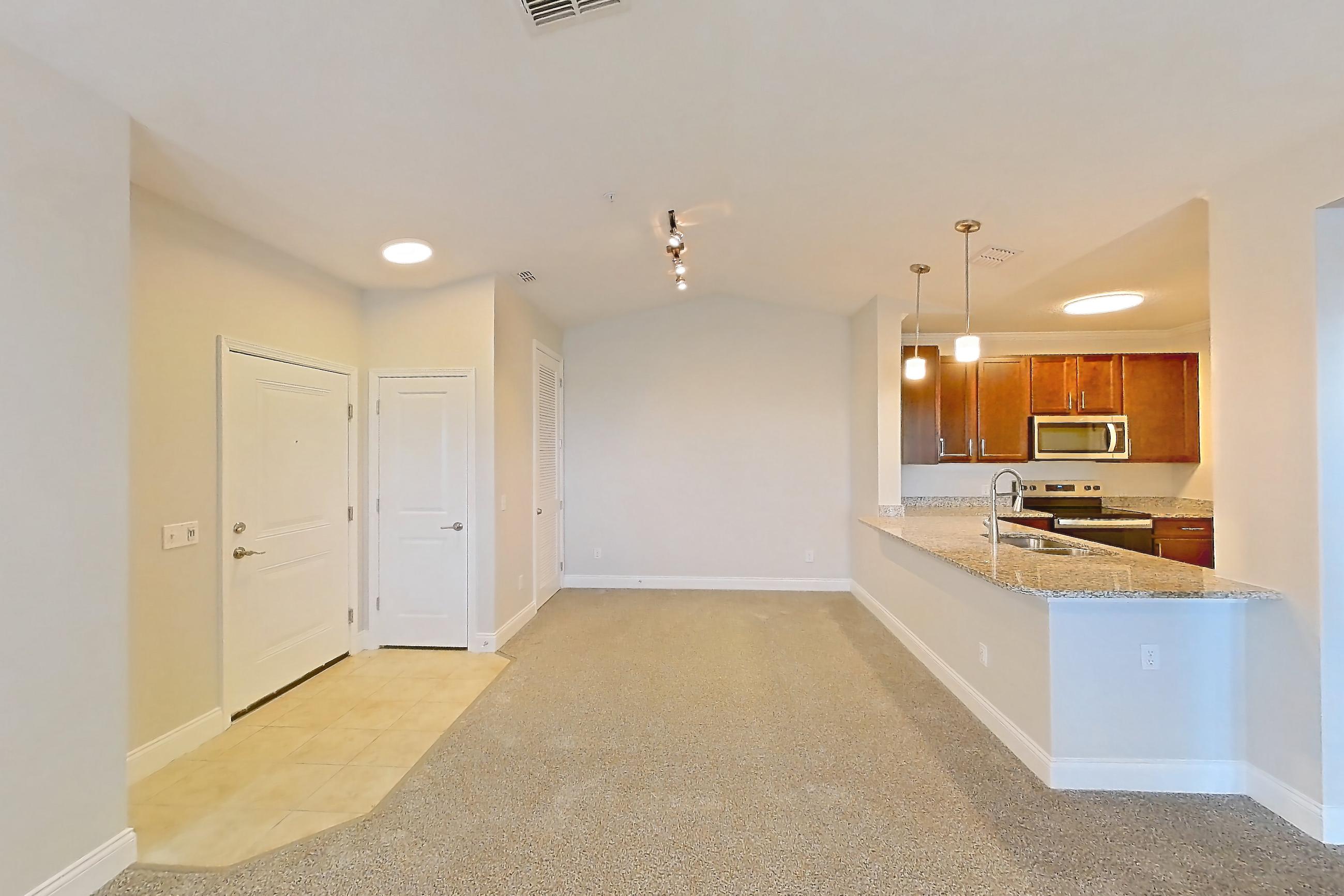 Living room with electric range, light carpet, light stone countertops, light tile flooring, oven/range, refrigerator, and stainless steel appliances, Apartment 1632 at Lake Nona Water Mark