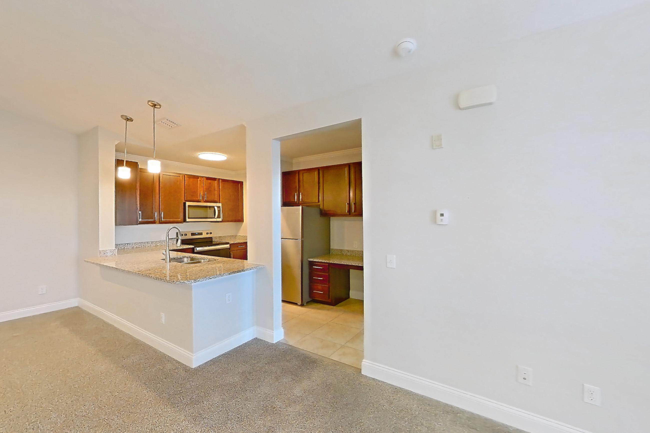 Living room with electric range, light carpet, light stone countertops, light tile flooring, oven/range, refrigerator, and stainless steel appliances, Apartment 1632 at Lake Nona Water Mark