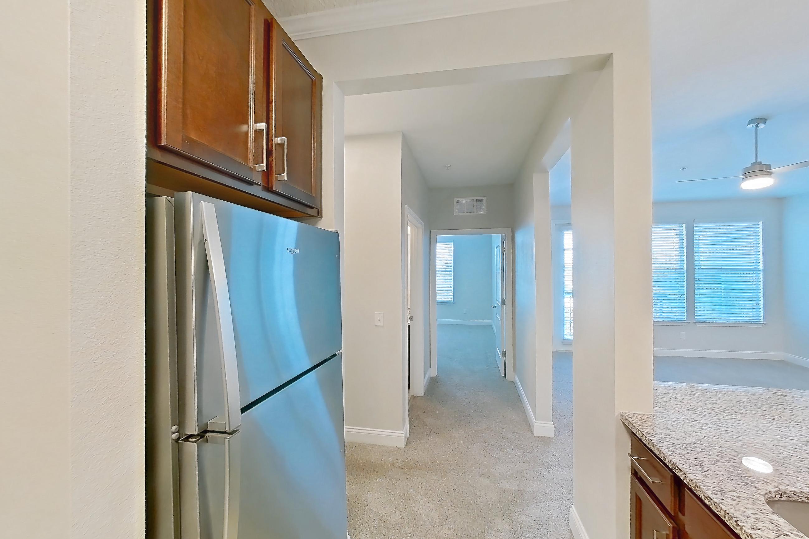 Kitchen with dishwasher, electric range, light carpet, light countertops, light stone countertops, light tile flooring, oven/range, refrigerator, and stainless steel appliances, Apartment 1933 at Lake Nona Water Mark