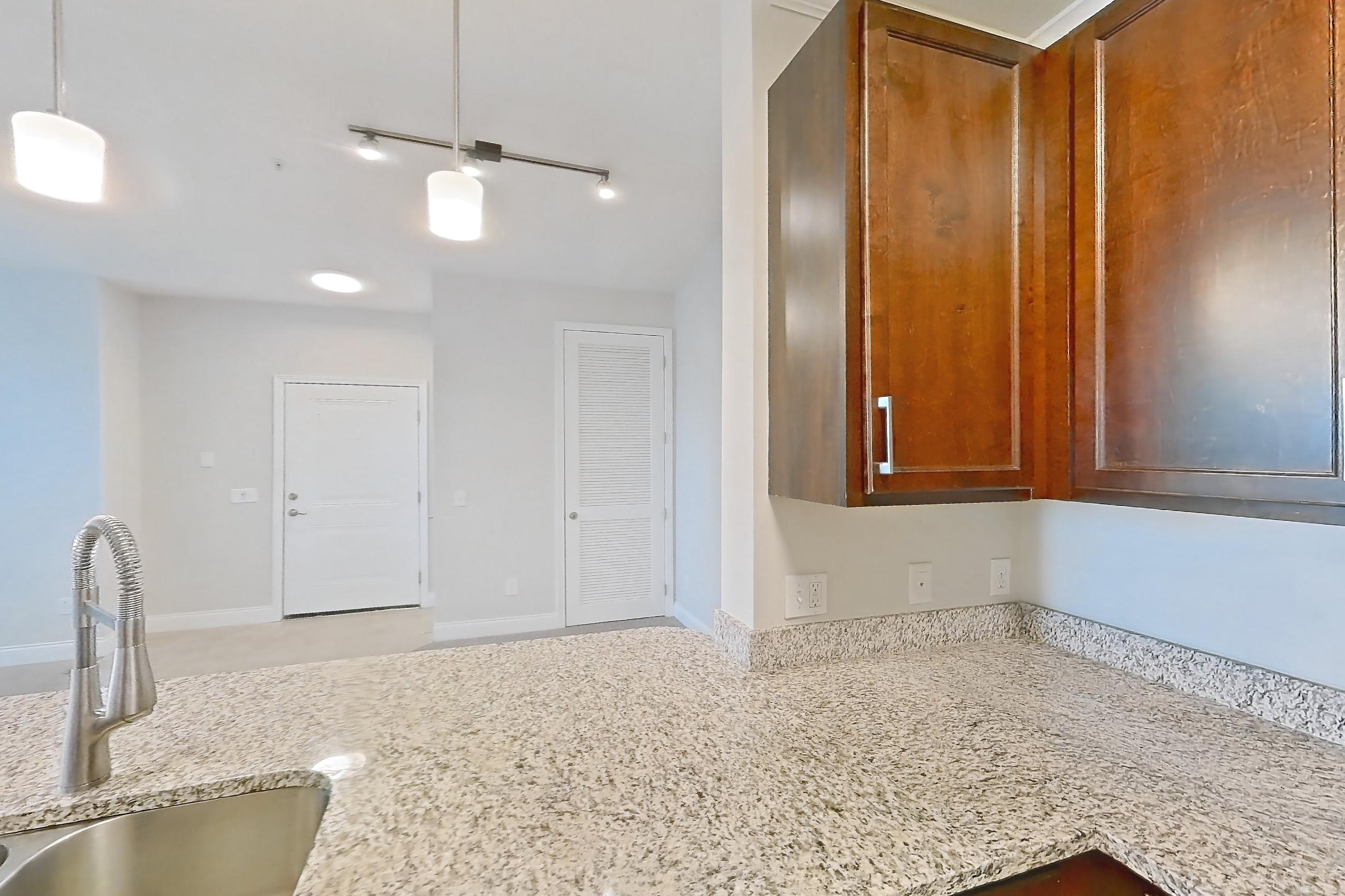 Kitchen with dishwasher, electric range, light carpet, light countertops, light stone countertops, light tile flooring, oven/range, refrigerator, and stainless steel appliances, Apartment 1933 at Lake Nona Water Mark