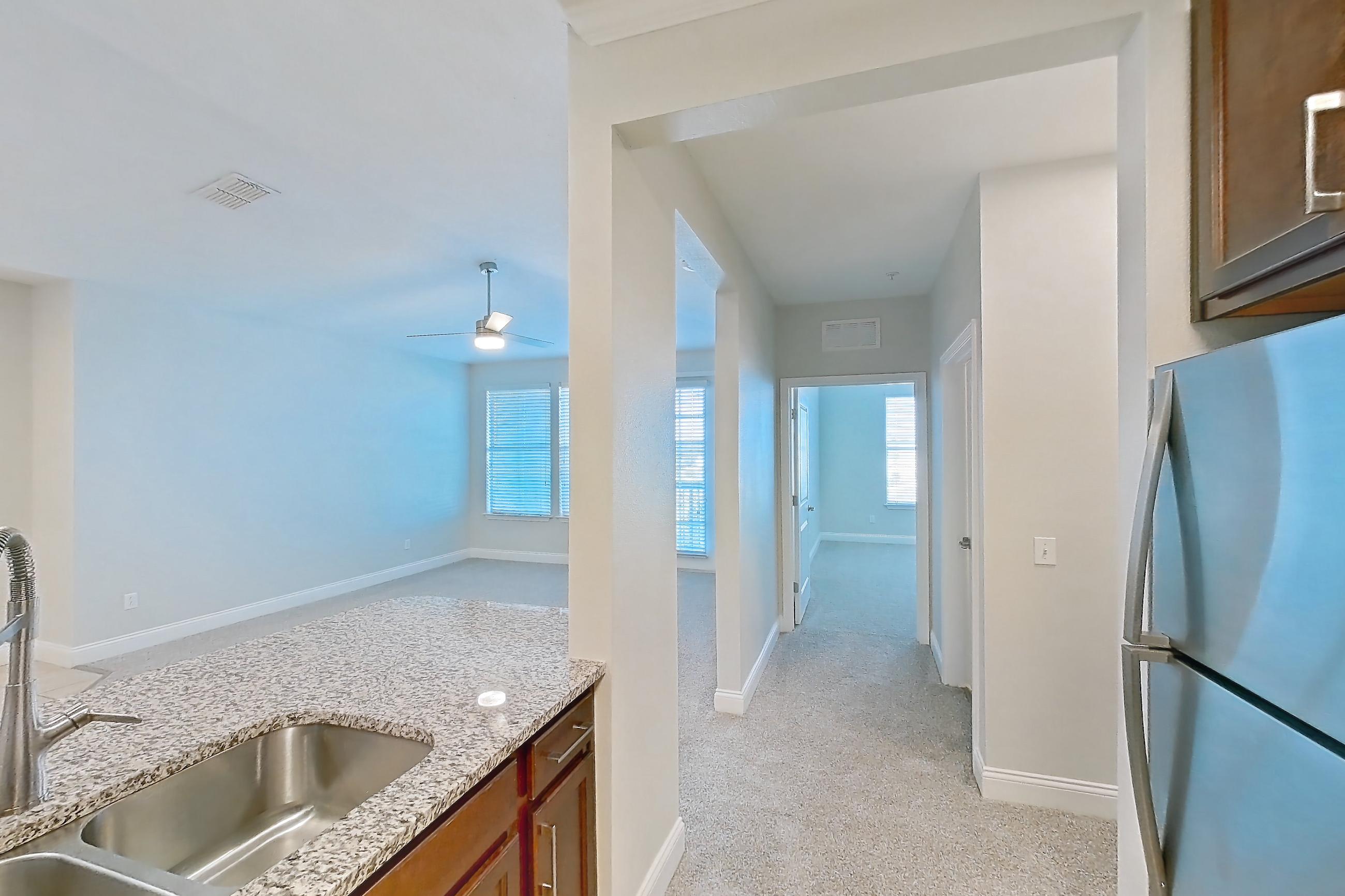 Kitchen with dishwasher, light carpet, light countertops, light stone countertops, light tile flooring, refrigerator, and stainless steel appliances, Apartment 2134 at Lake Nona Water Mark