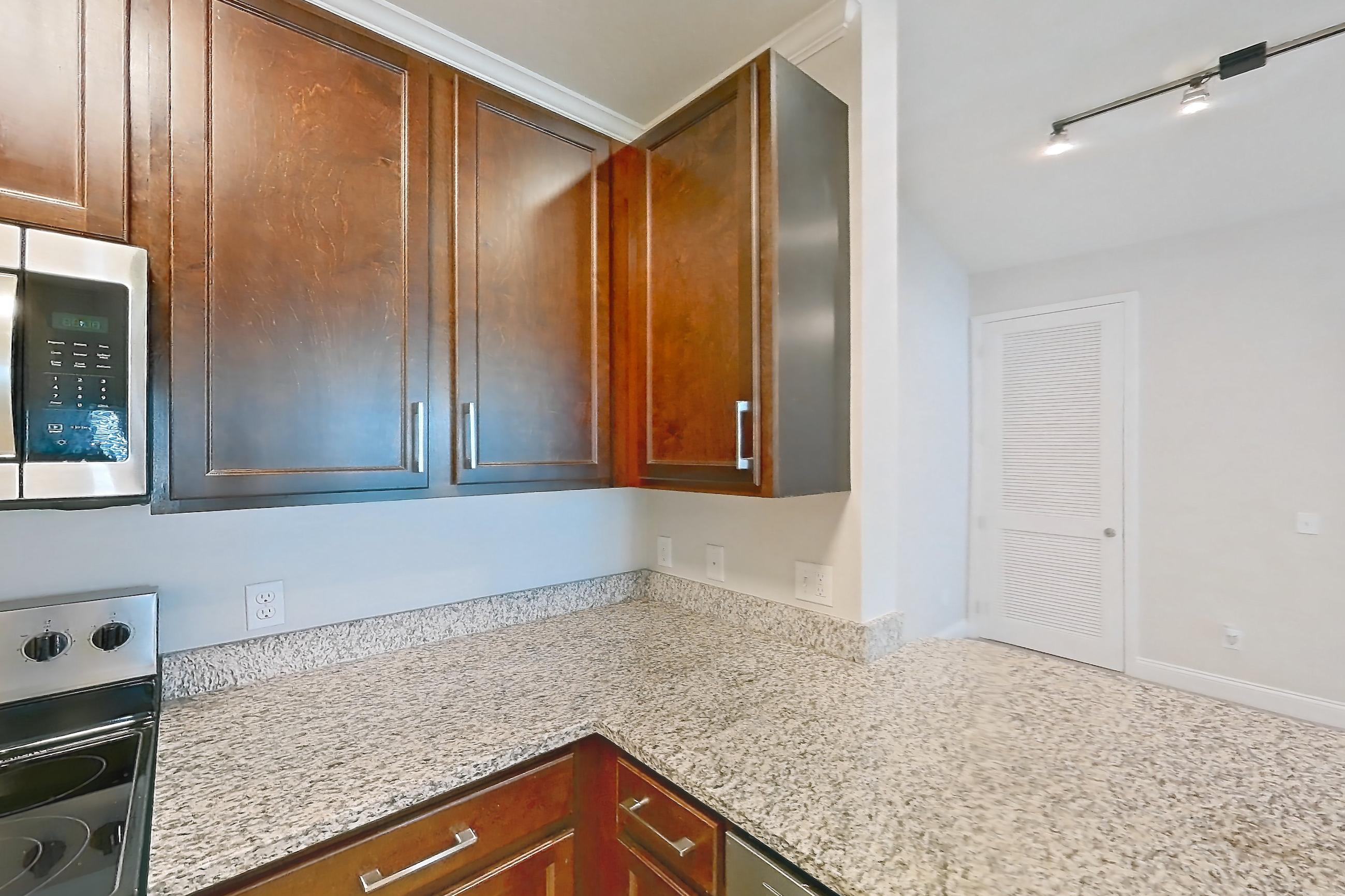 Kitchen with dishwasher, light carpet, light countertops, light stone countertops, light tile flooring, refrigerator, and stainless steel appliances, Apartment 2134 at Lake Nona Water Mark