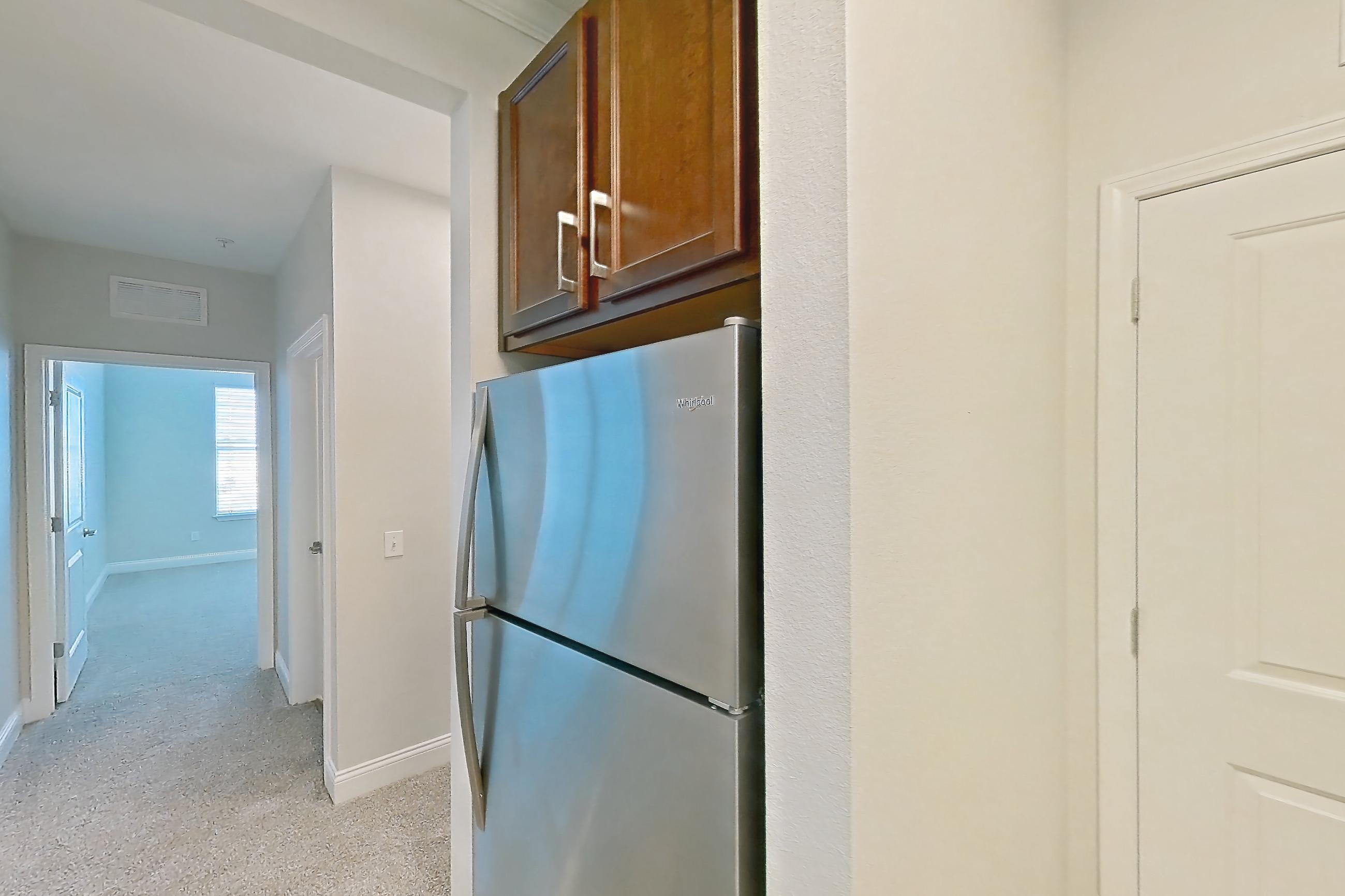 Kitchen with dishwasher, light carpet, light countertops, light stone countertops, light tile flooring, refrigerator, and stainless steel appliances, Apartment 2134 at Lake Nona Water Mark