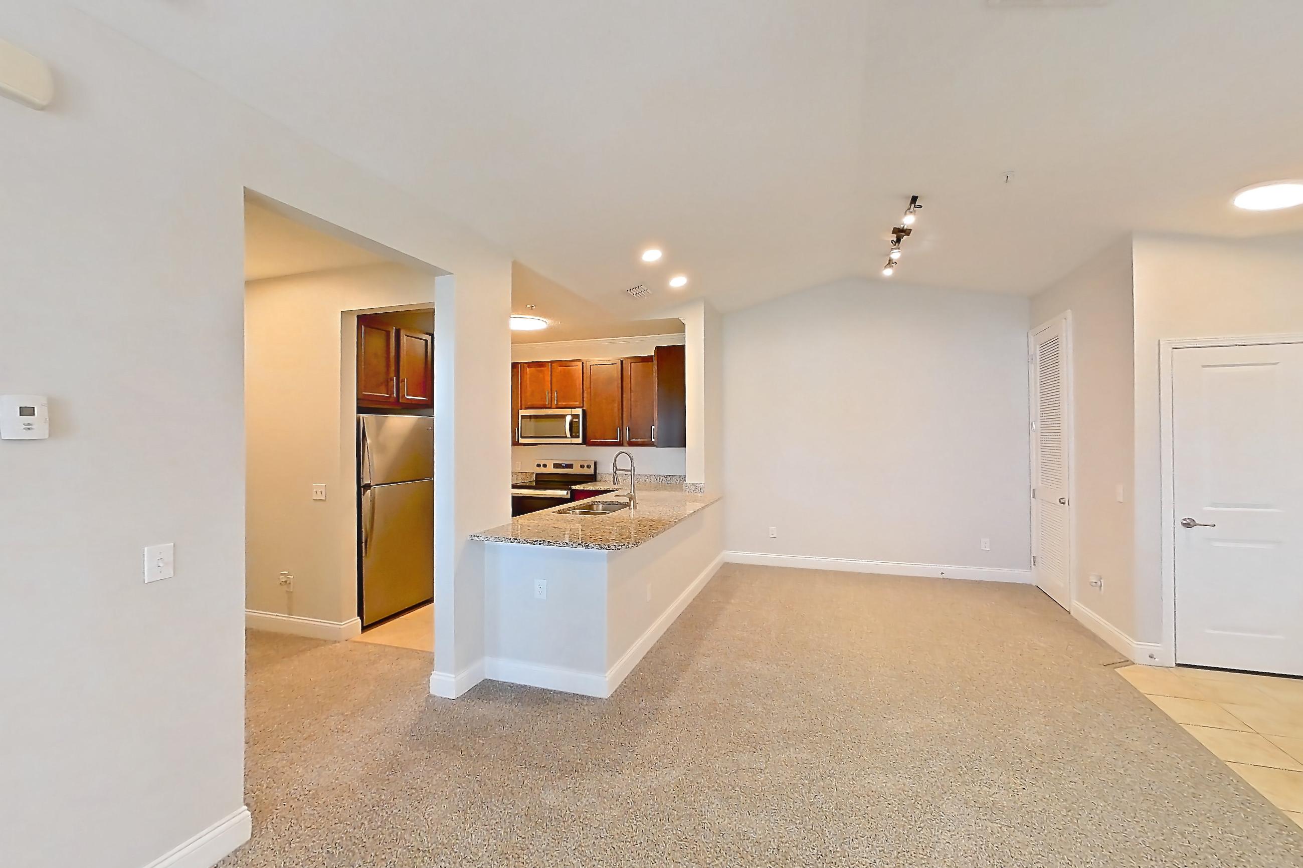Living room with electric range, light carpet, light stone countertops, light tile flooring, oven/range, refrigerator, and stainless steel appliances, Apartment 2134 at Lake Nona Water Mark