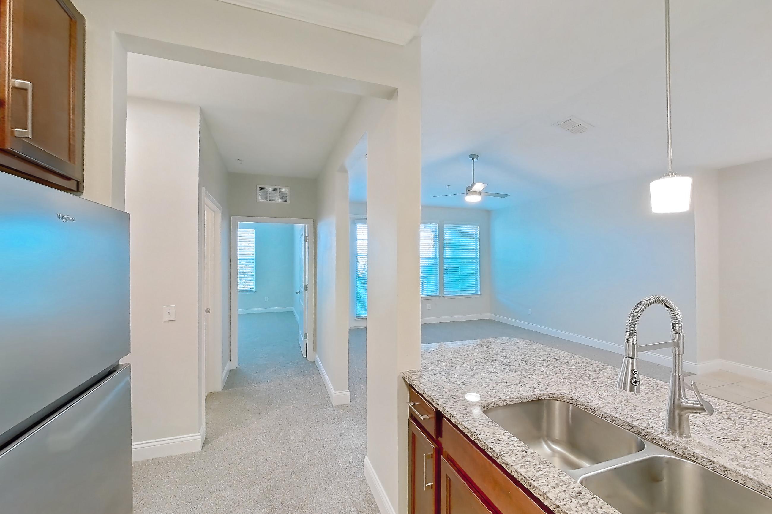 Kitchen with dishwasher, light carpet, light stone countertops, light tile flooring, refrigerator, and stainless steel appliances, Apartment 2233 at Lake Nona Water Mark