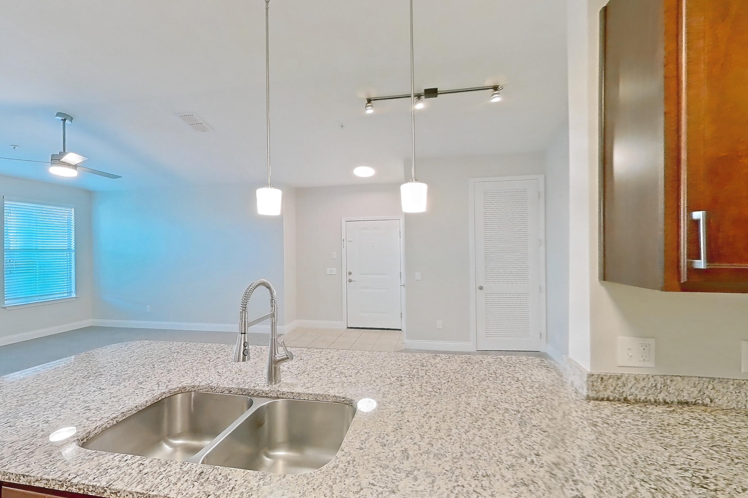 Kitchen with dishwasher, light carpet, light stone countertops, light tile flooring, refrigerator, and stainless steel appliances, Apartment 2233 at Lake Nona Water Mark
