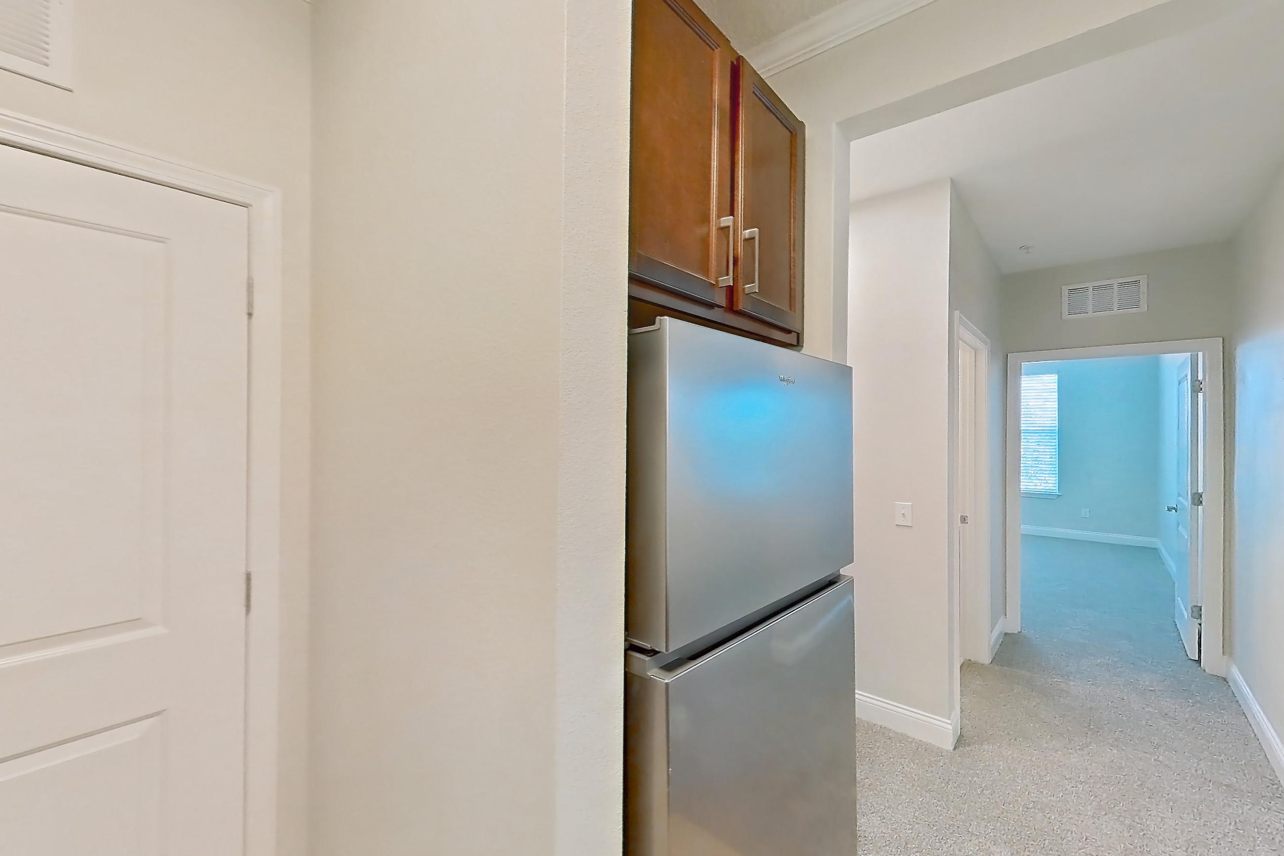 Kitchen with dishwasher, light carpet, light stone countertops, light tile flooring, refrigerator, and stainless steel appliances, Apartment 2233 at Lake Nona Water Mark
