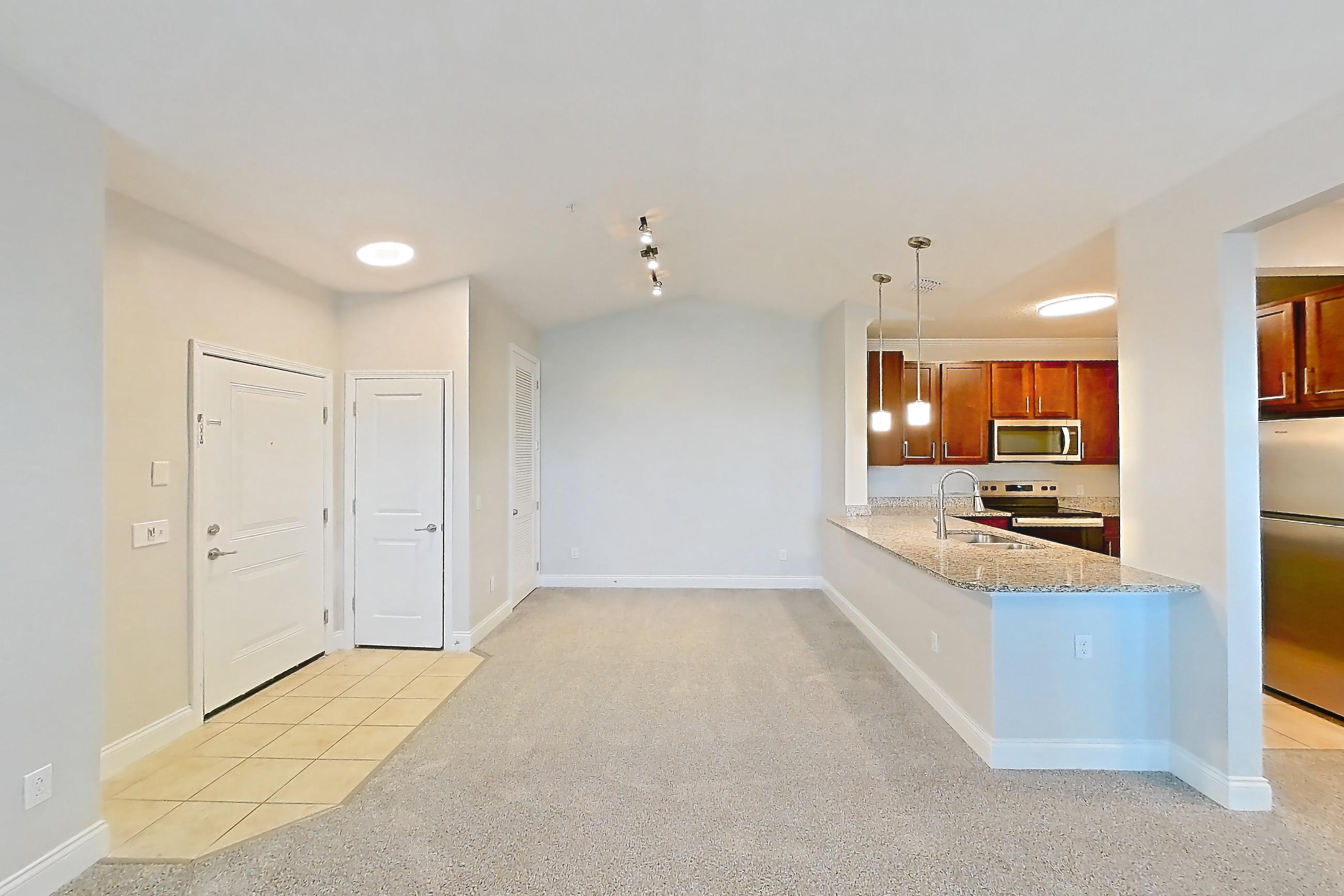 Living room with electric range, light carpet, light tile flooring, oven/range, refrigerator, and stainless steel appliances, Apartment 2233 at Lake Nona Water Mark