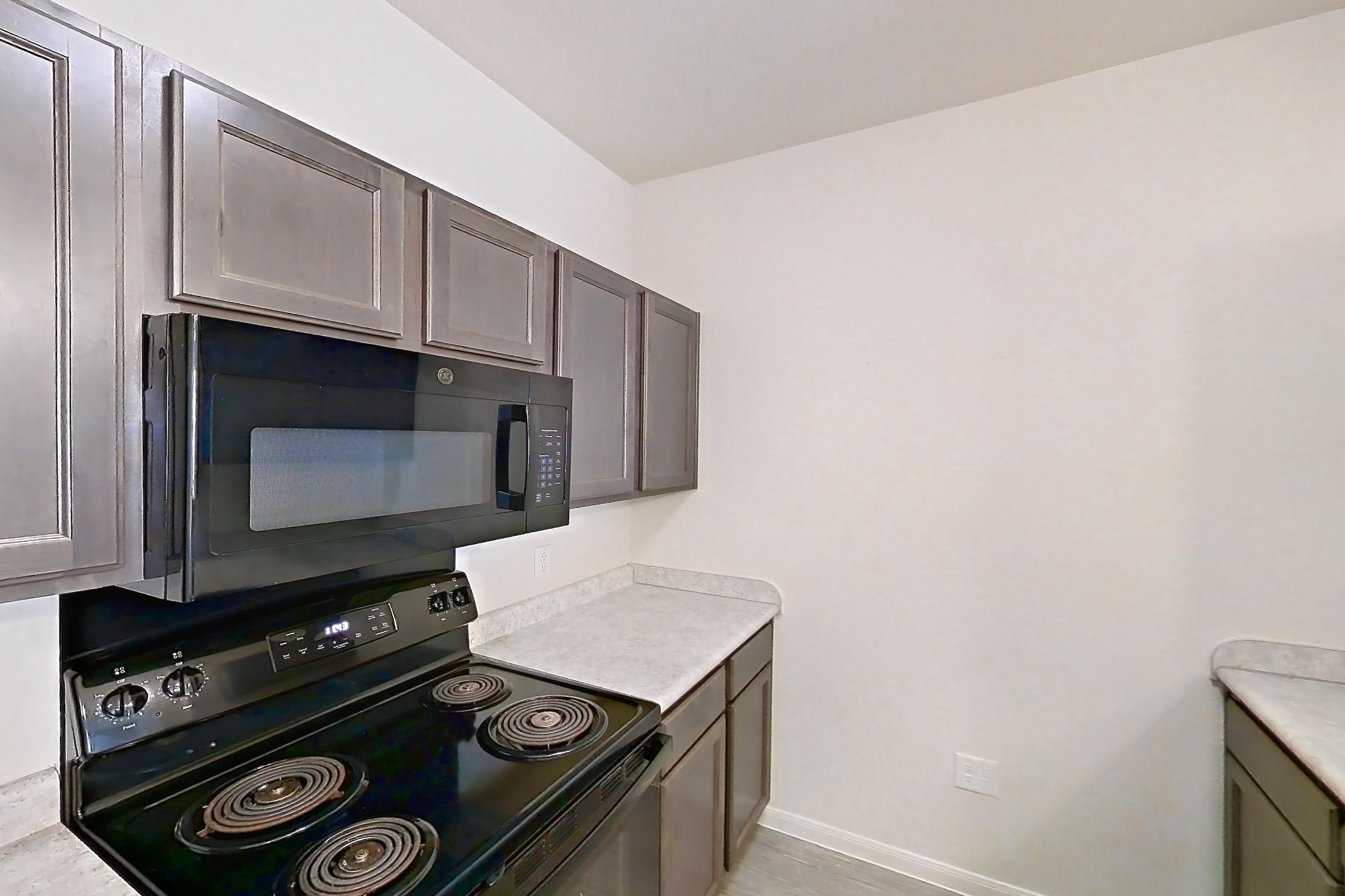 Kitchen with black appliances, electric range, light countertops, microwave, oven/range, and refrigerator, Apartment 5107 at Residences of Stillwater