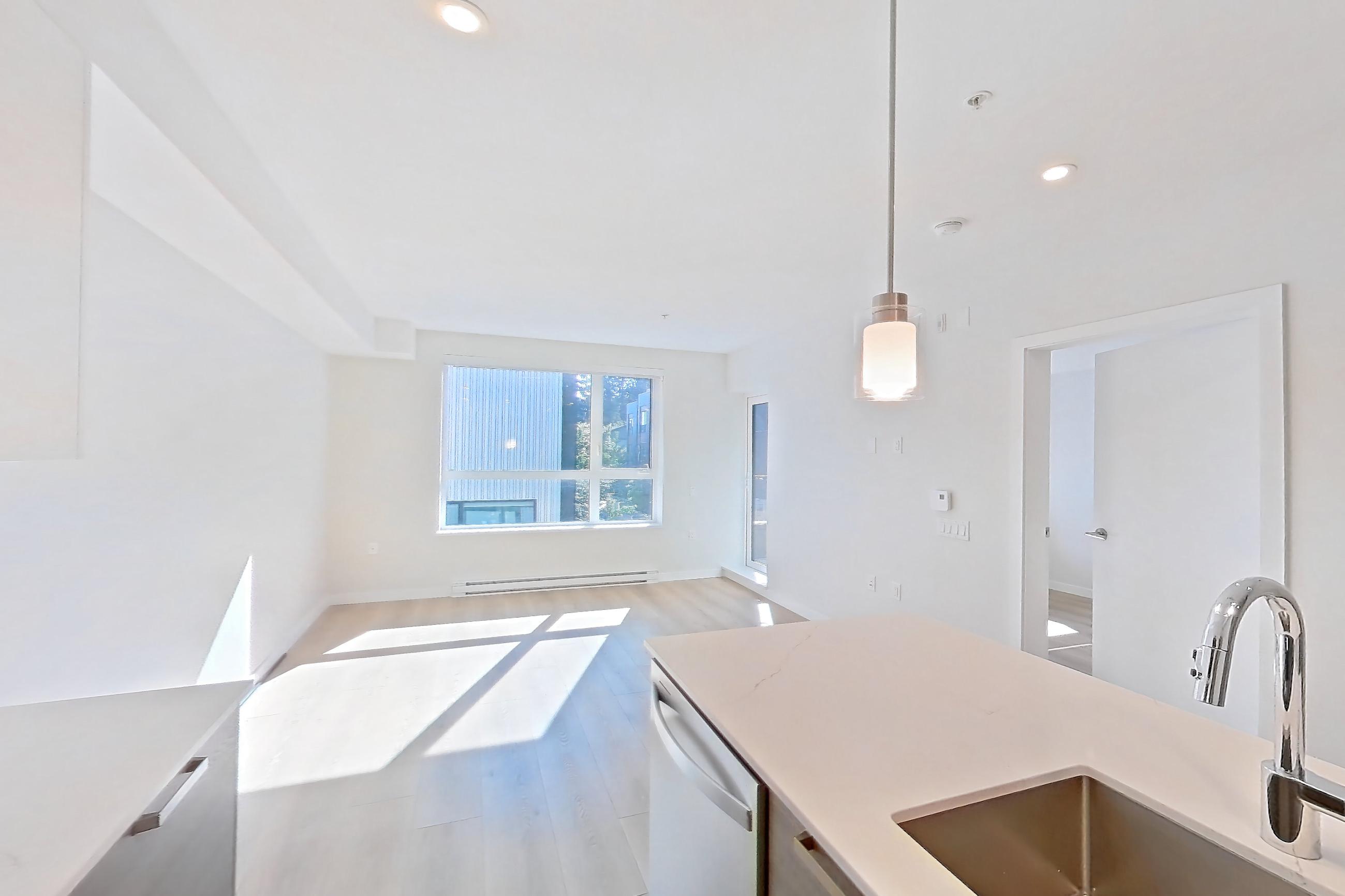 Kitchen with baseboard heating, black appliances, cooktop, dishwasher, electric cooktop, kitchen island, light stone countertops, light wood-finish flooring, oven/range, stainless steel appliances, and white appliances, Apartment A-204 at Hendry Place